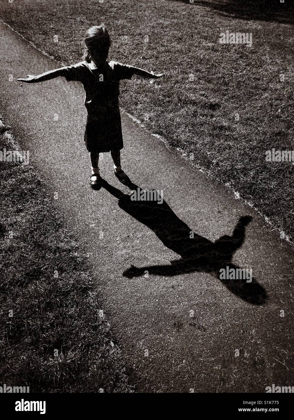 L'ombra di un 5 anno di età bambino come Lei alza le braccia e cerca di creare una "t" forma. Un effetto di grunge immagine con molteplici usi. Credito foto - © COLIN HOSKINS. Foto Stock