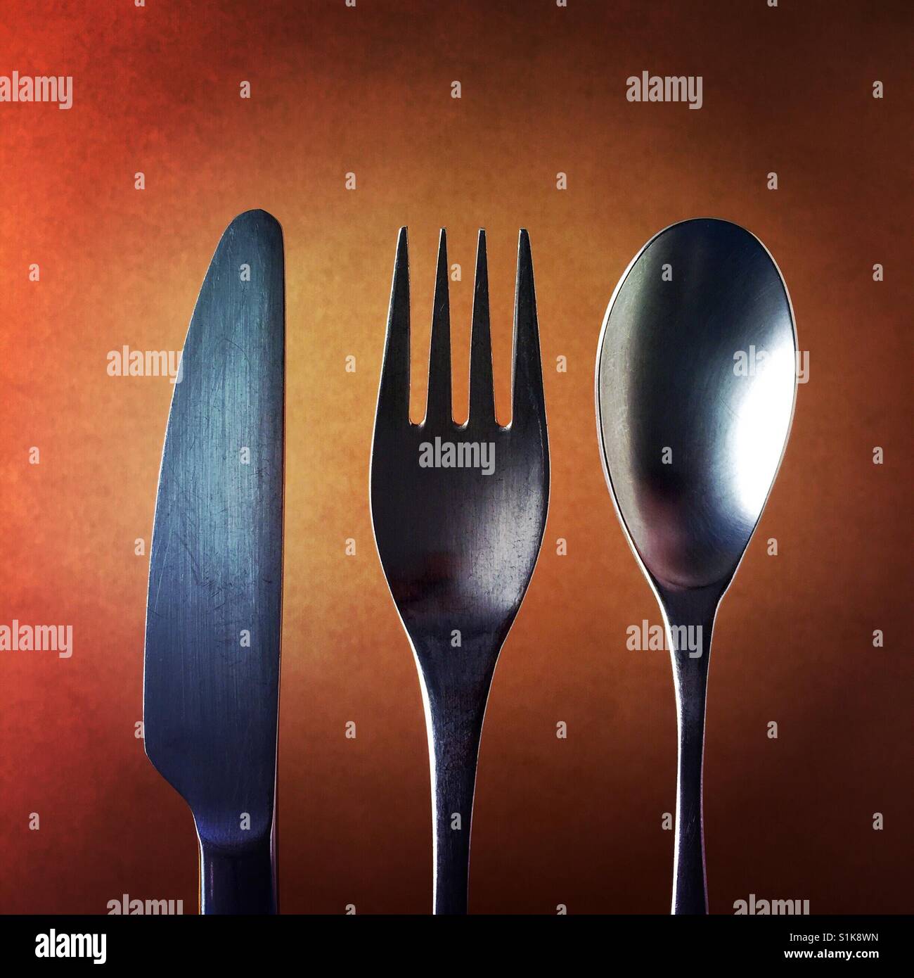 Un'immagine ravvicinata di un coltello e una forchetta e un cucchiaio sopra uno sfondo marrone Foto Stock