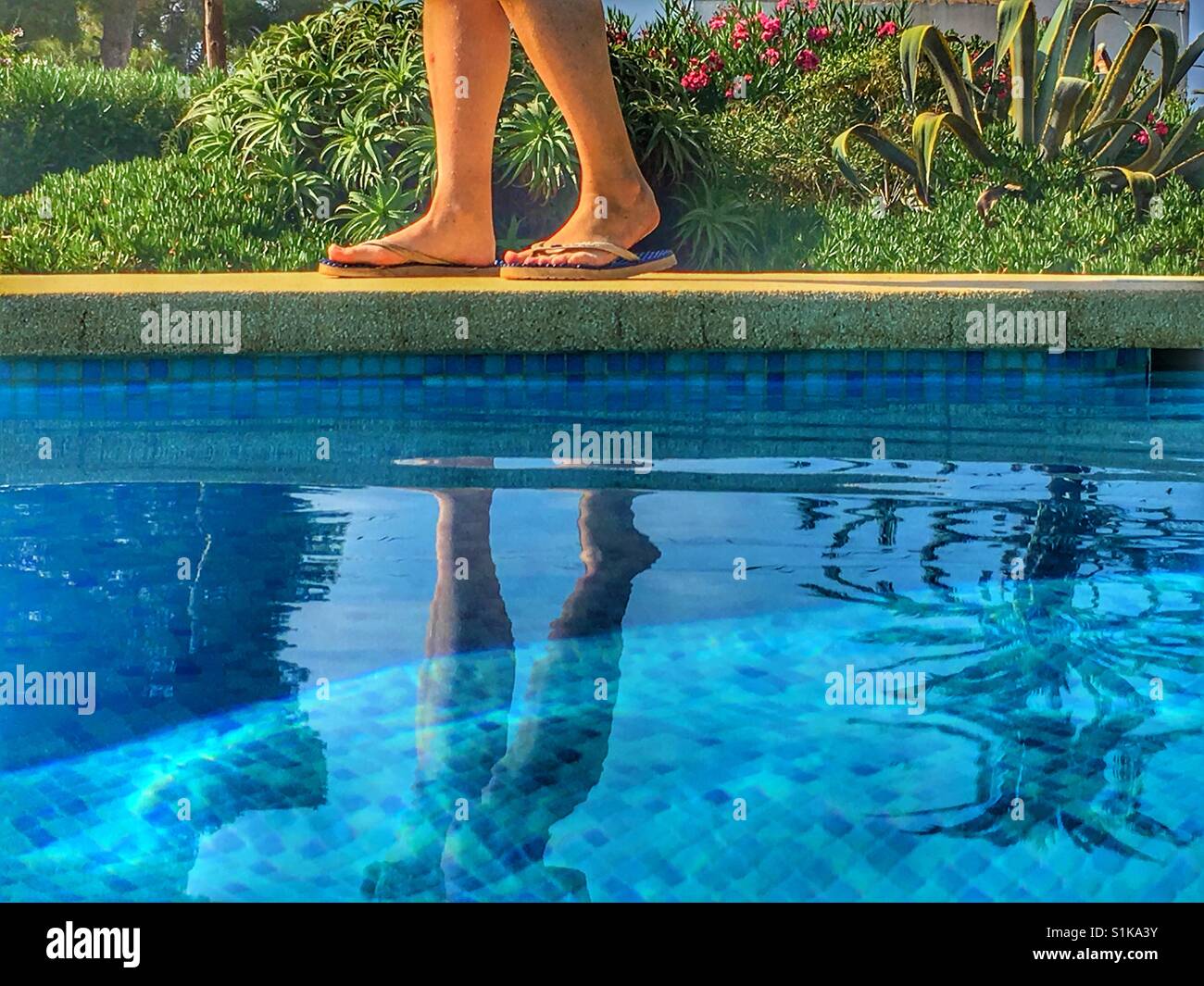 Donna in flipflops, camminare a bordo piscina Foto Stock