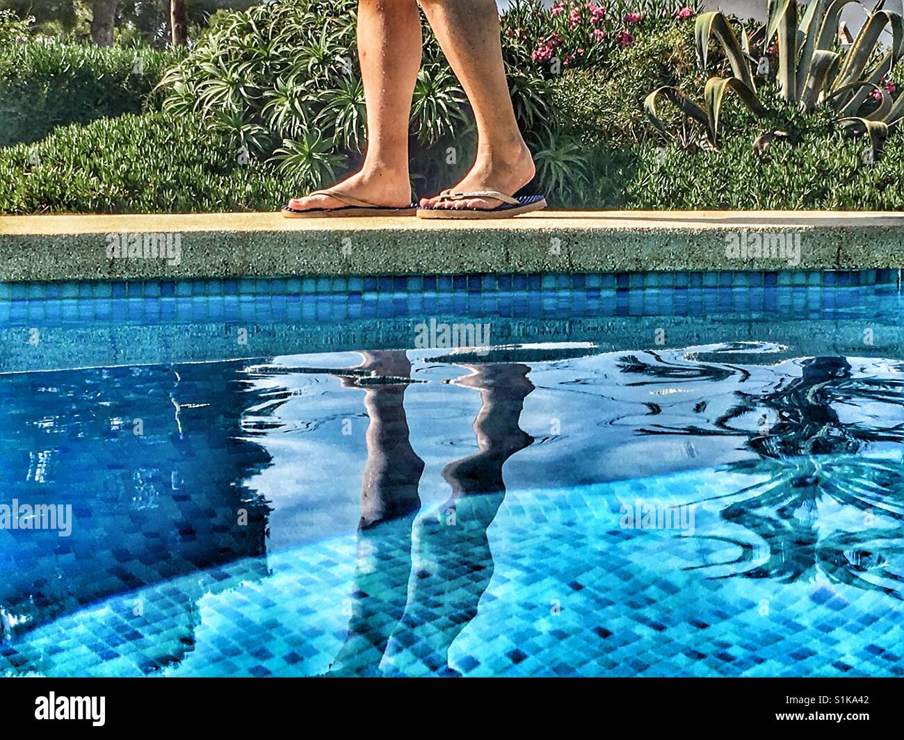 Donna in flipflops camminando sul bordo della piscina Foto Stock