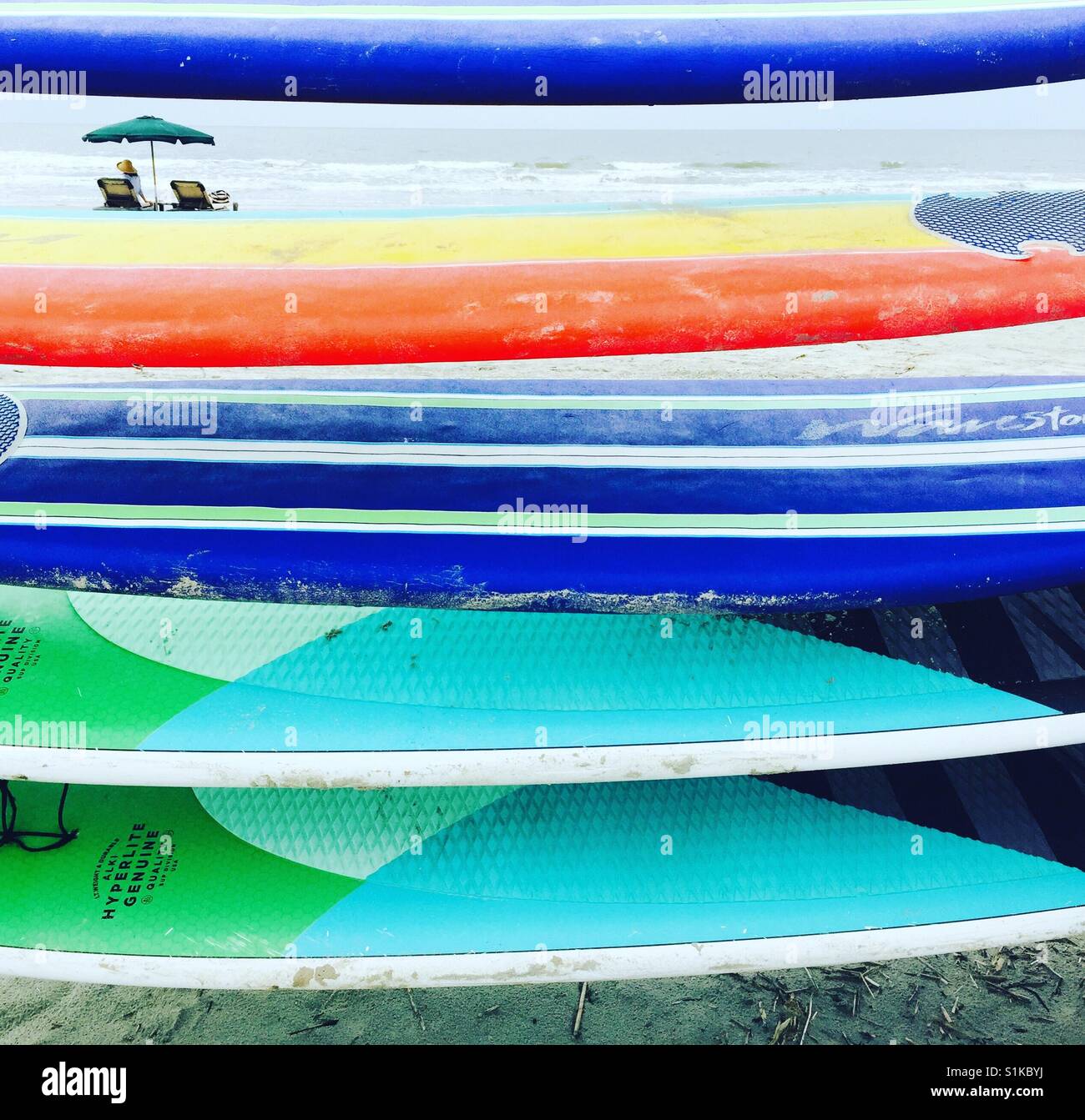 Una pila di colorate tavole da surf e paddle boards. Foto Stock