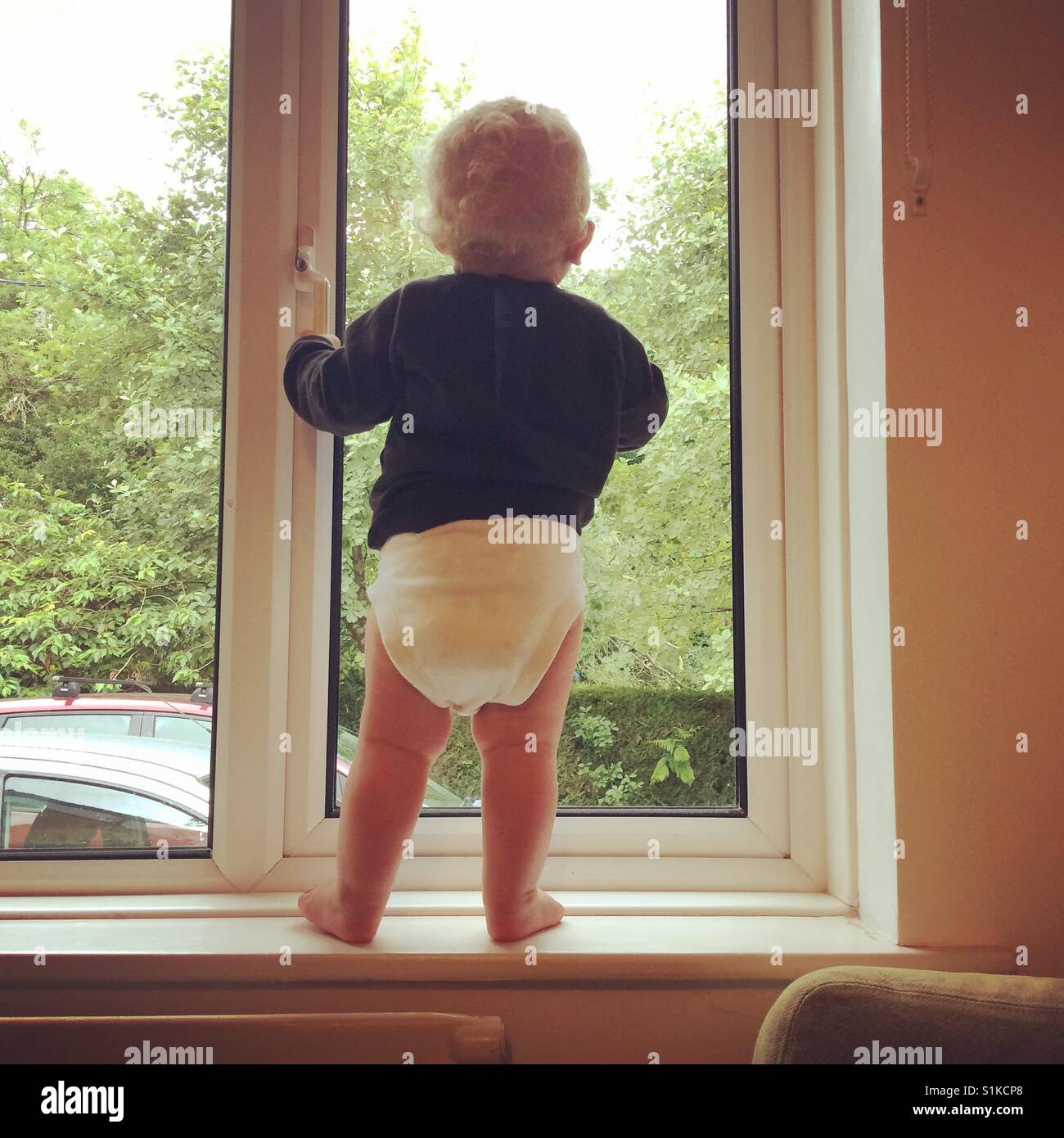 Undici mesi baby boy in piedi in una finestra. Foto Stock