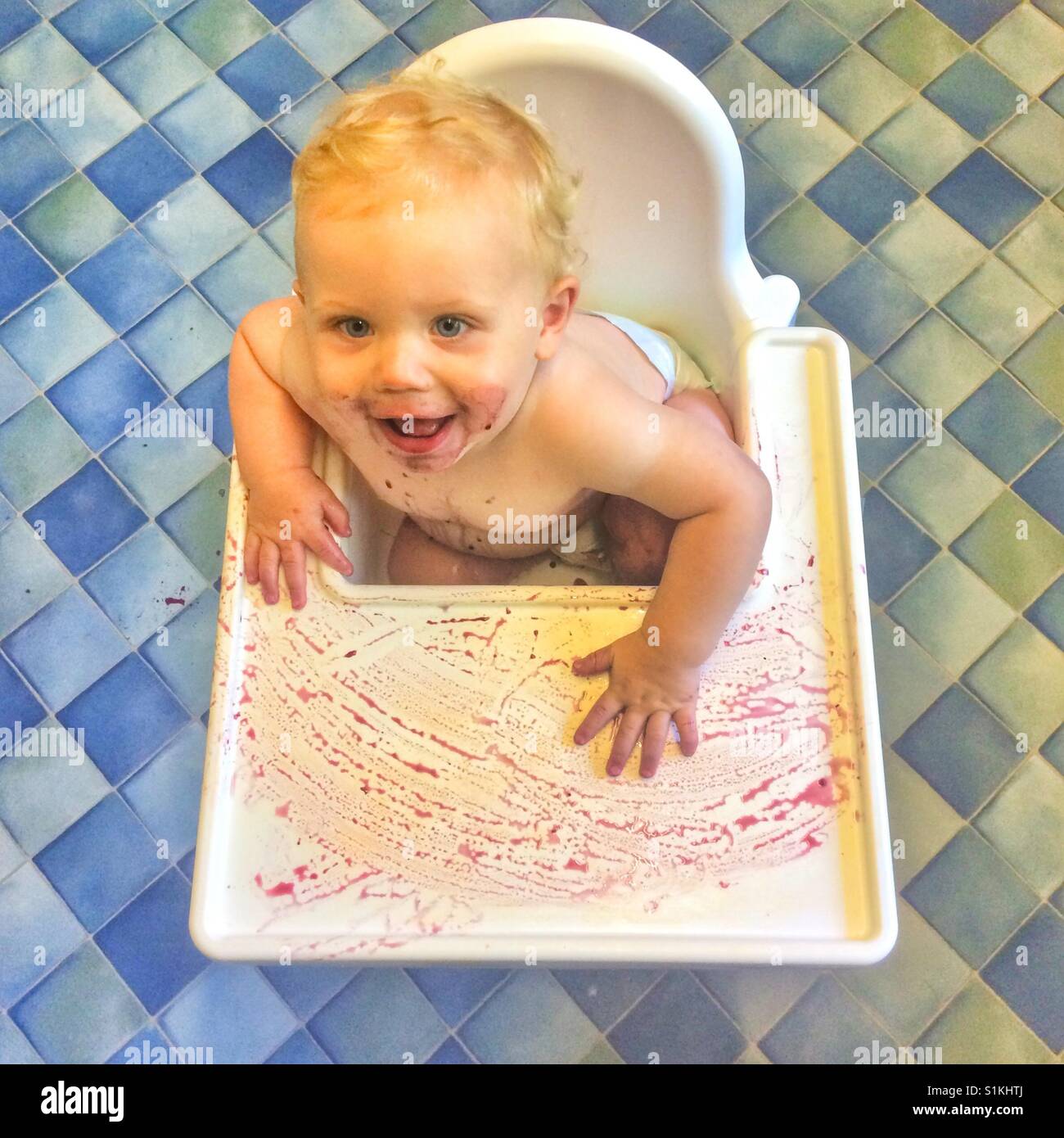 Undici mesi di età bambino seduto in un confuso sedia alta Foto Stock