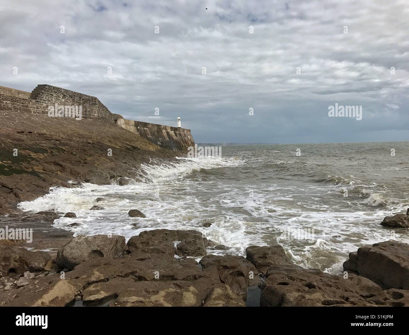 Porthcawl, Galles - 31 Luglio 2017: la marea sul giro inizia a lavare fino contro la parete del porto Foto Stock