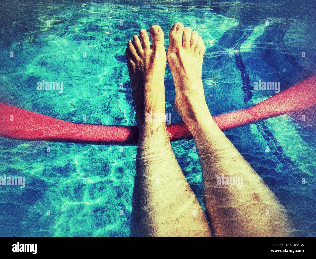La donna per le gambe su un pool noodle, flottante in una piscina - Immagine stock catturata con smartphone