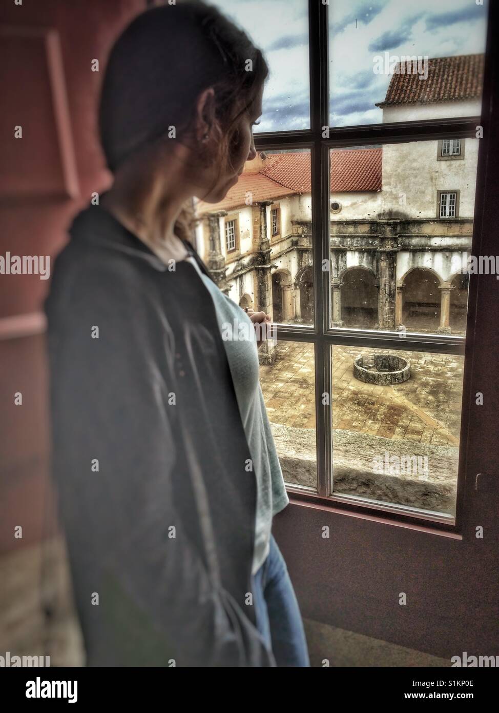 Malinconici donna che guarda fuori dalla finestra di un castello in Portogallo. Foto Stock