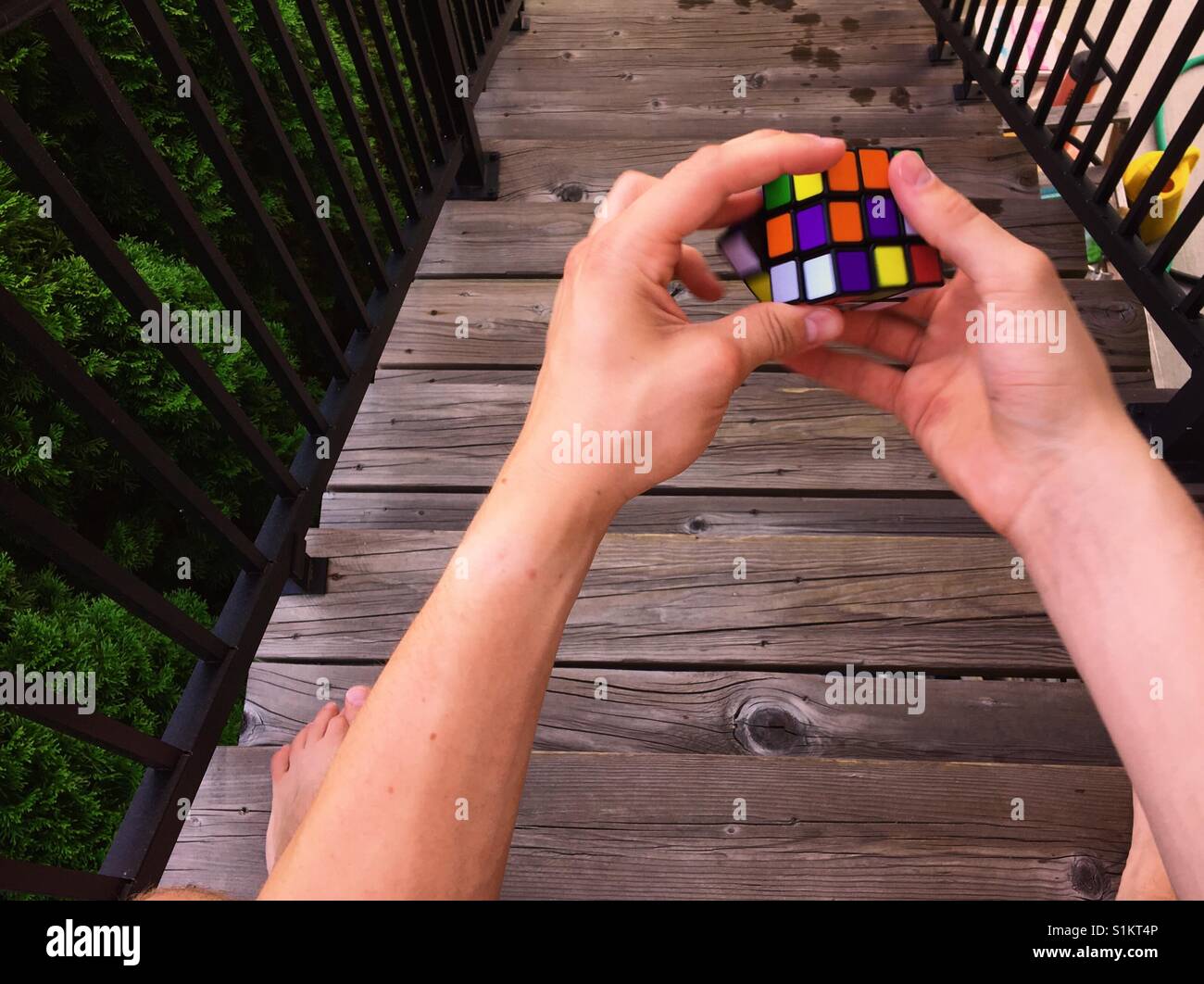 Giovane uomo risolvere un cubo di Rubik in cima a scale di legno. Foto Stock