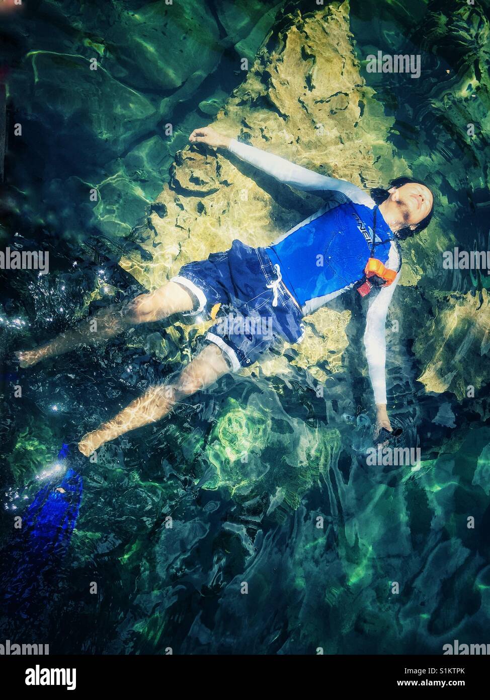 L'uomo galleggianti in chiare acque del lago il Kayangan su Coron Island nelle Filippine Foto Stock
