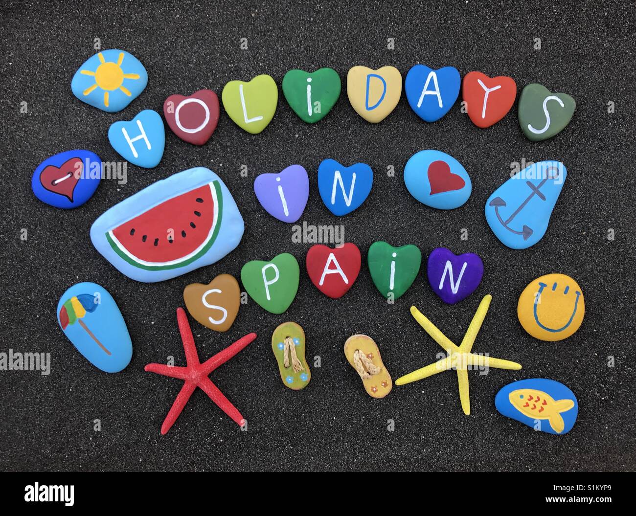 Vacanze in Spagna, pietre colorate composizione sulla sabbia nera vulcanica Foto Stock