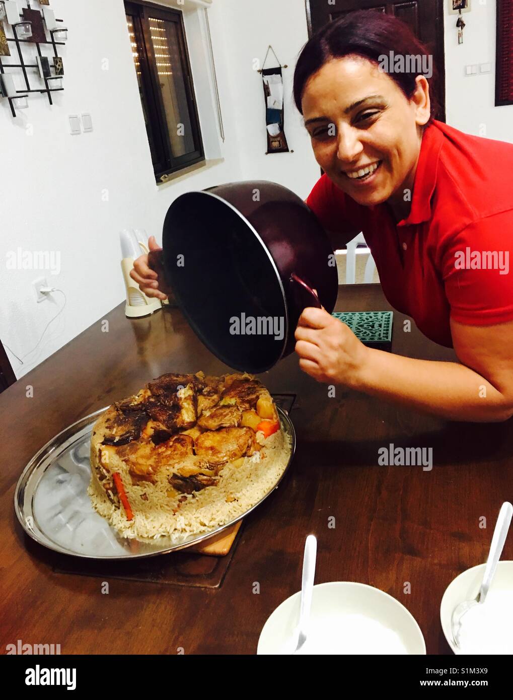 Una donna Palestinese che serve Maqluba - un arabo tradizionale piatto di riso che è ribaltata sottosopra quando viene servita. Foto Stock