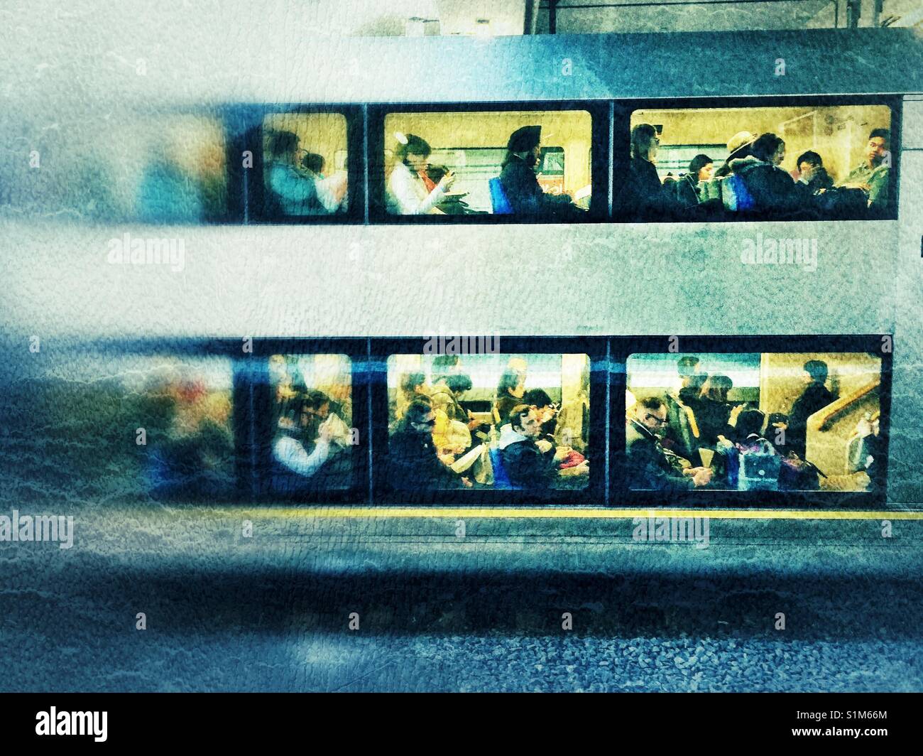 Vista di persone in più finestre del treno carrello durante le ore di punta di Sydney, Australia. Uomini e donne di diverse età e cultura gruppi riempire il tempo delle attività durante spostamenti giornalieri per lavoro Foto Stock