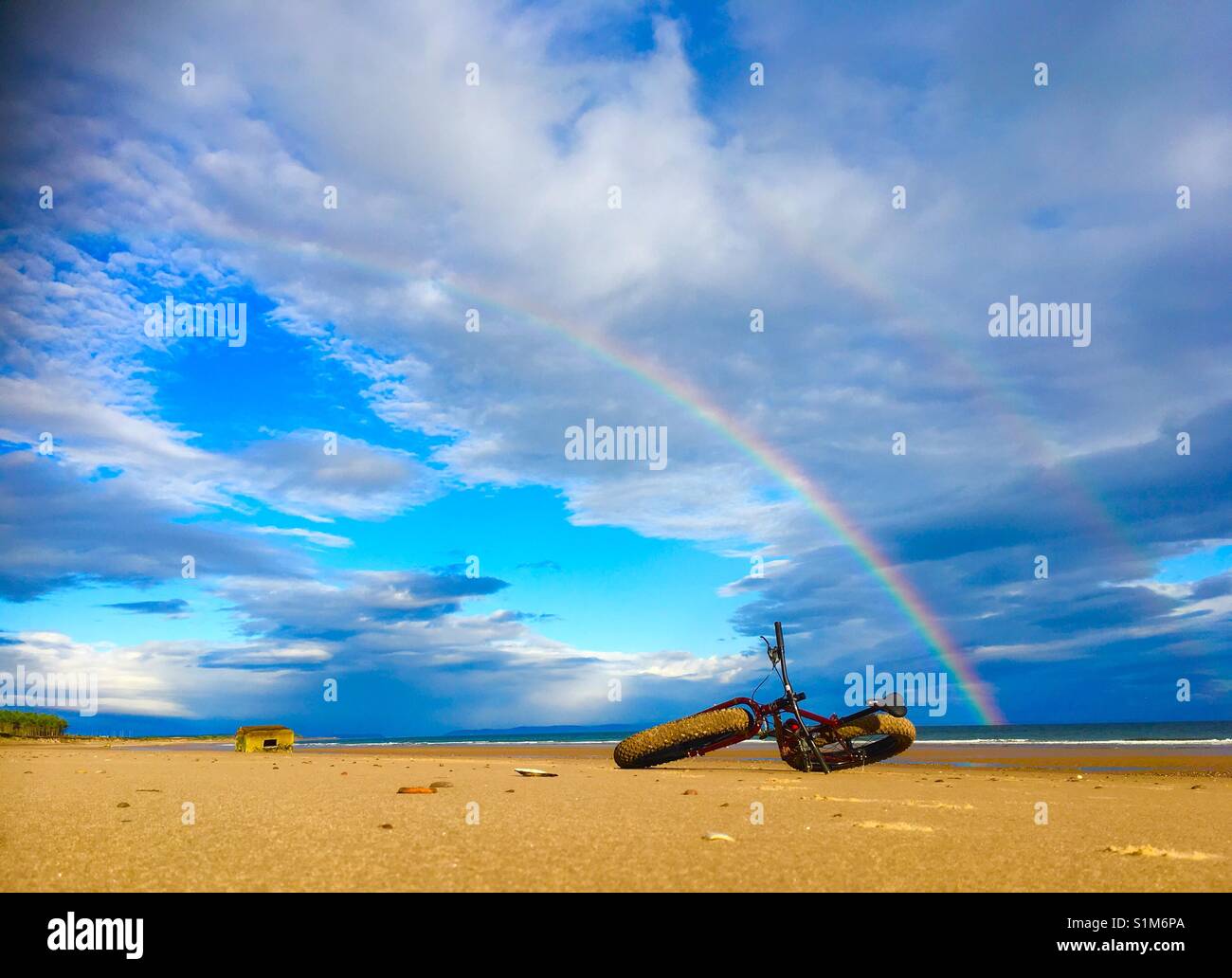 Fatbike sulla spiaggia con rainbow Foto Stock