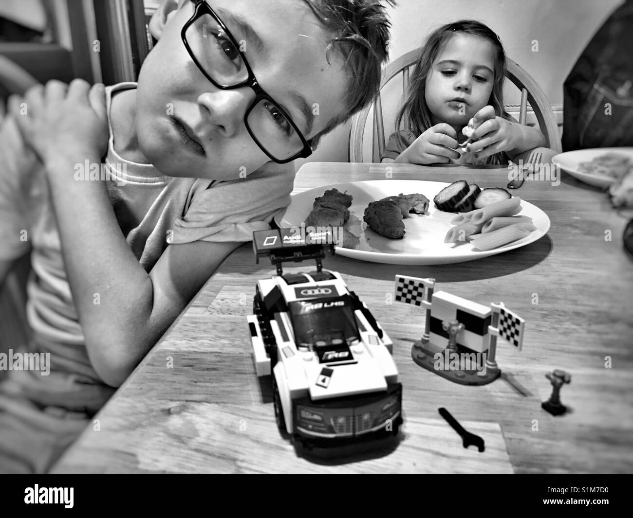 Ragazzo in posa con il suo nuovo Lego Audi Auto Racing mentre la sorella gioca con il suo nuovo giocattolo. Foto Stock