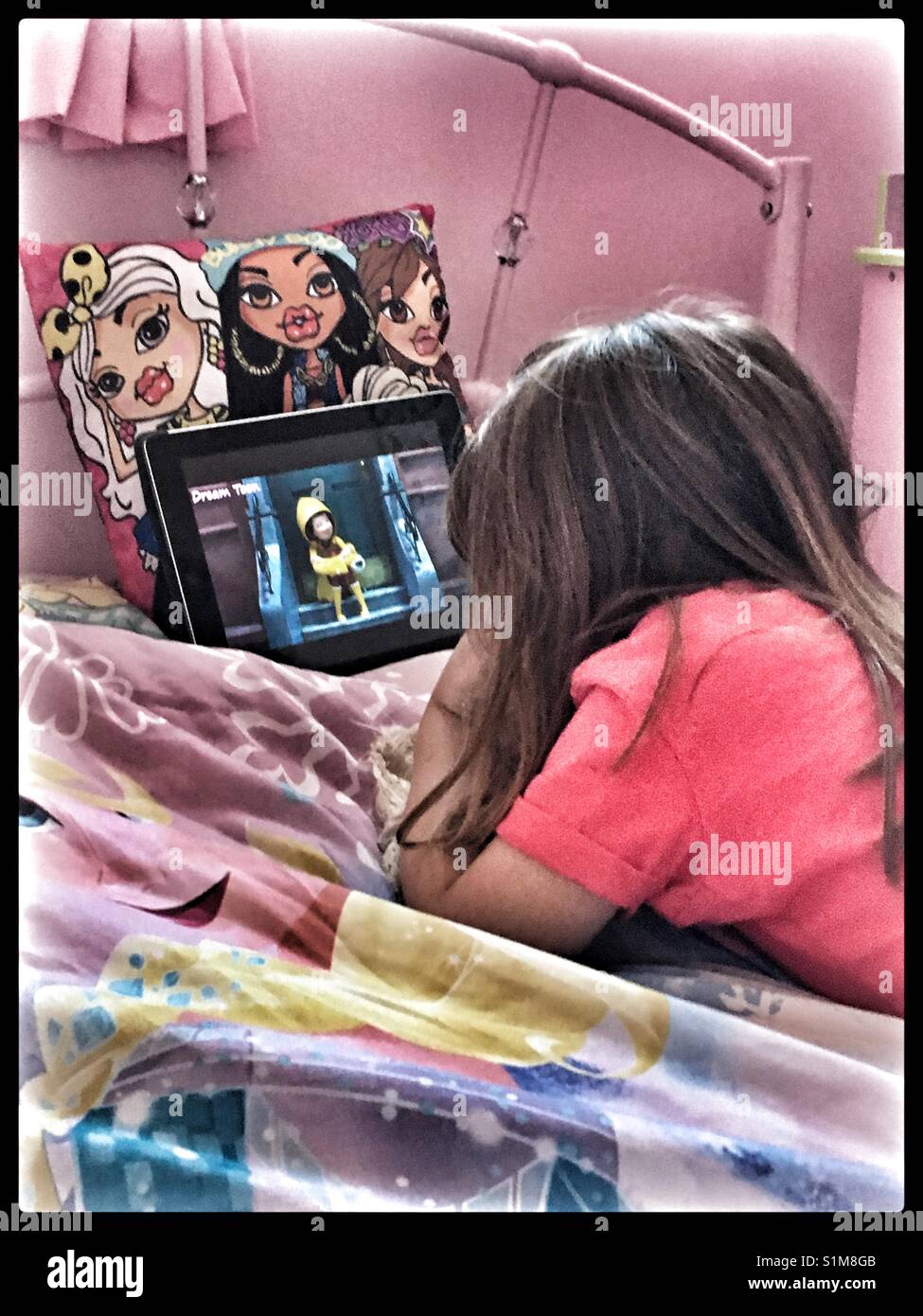 Giovane ragazza che stabilisce nel suo letto a guardare un iPad. Foto Stock