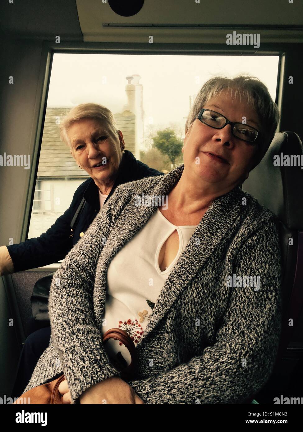 Due donne senior amici sul bus al giorno di viaggio Jurassic Coast Dorset Inghilterra a Lyme Regis Foto Stock