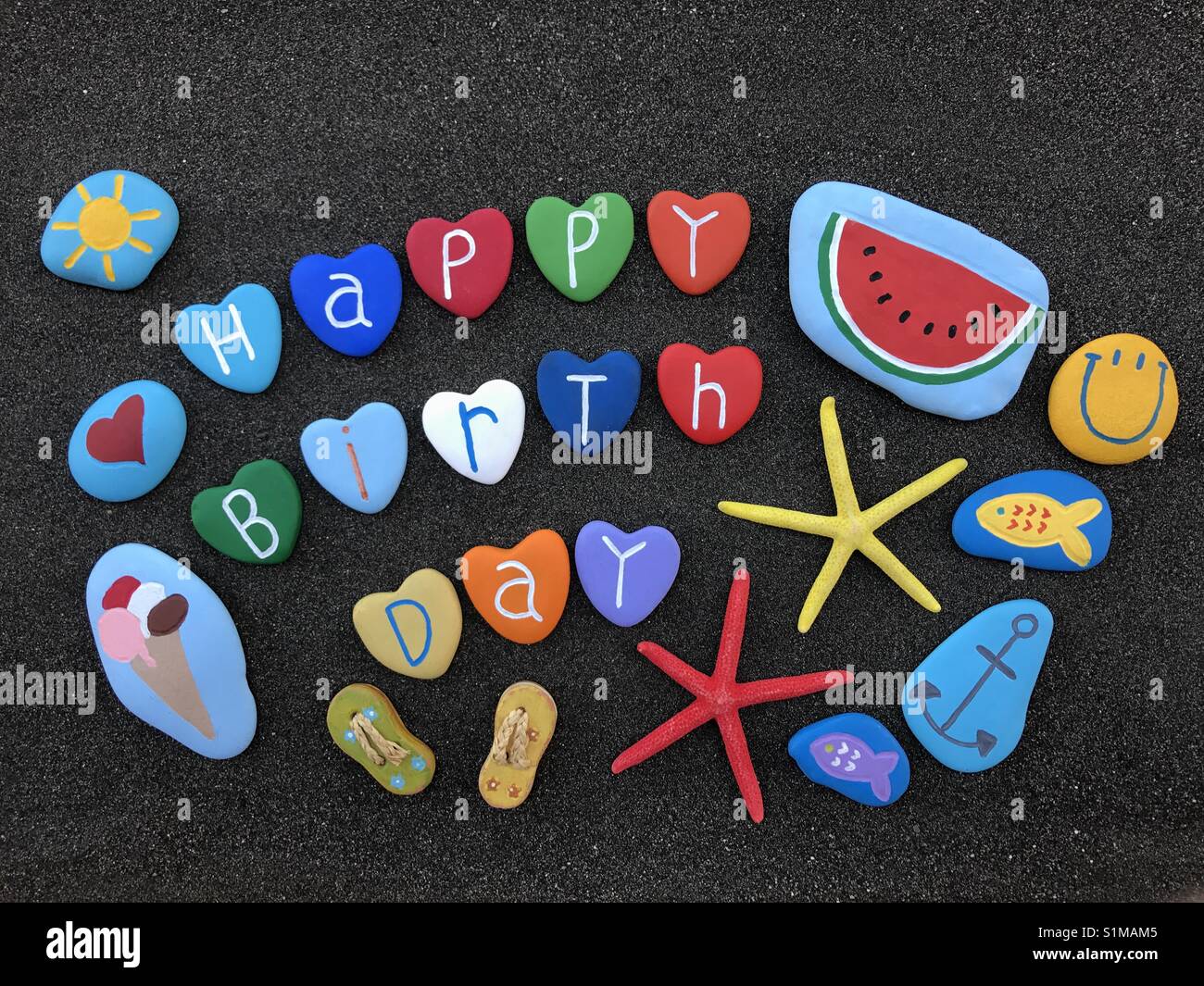 Buon compleanno con pietre design sulla sabbia nera vulcanica - Immagine stock catturata con smartphone
