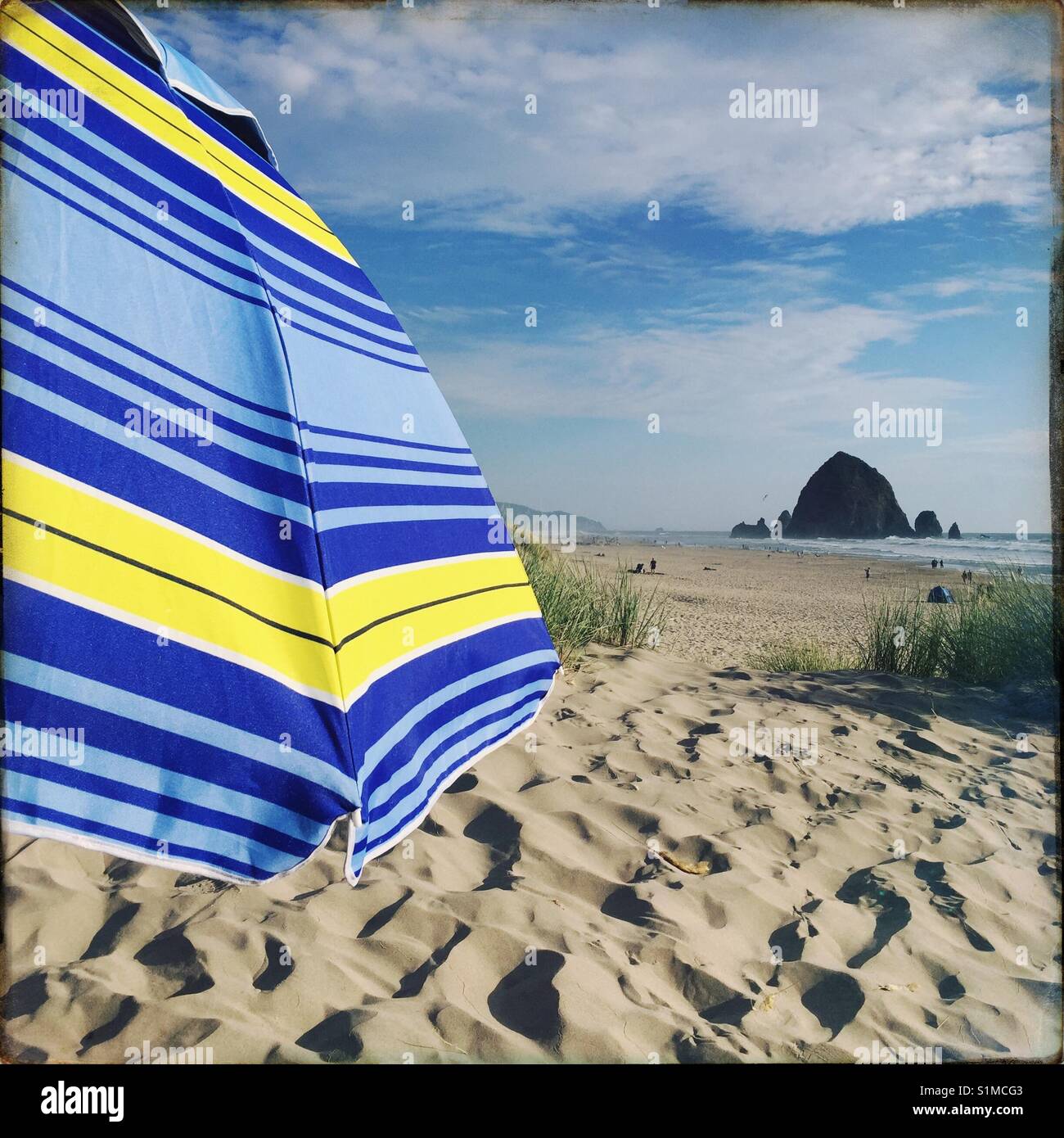 Una vista di Haystack Rock da un ombrellone sulla spiaggia di cannone o. Foto Stock