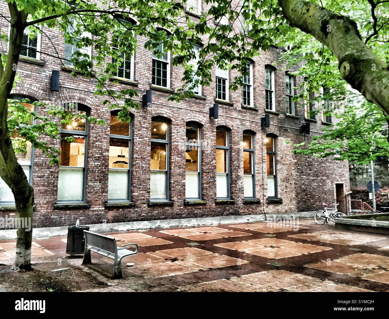 Banco in un parco di fronte a un vecchio edificio in mattoni in Yaletown in Vancouver - Immagine stock catturata con smartphone