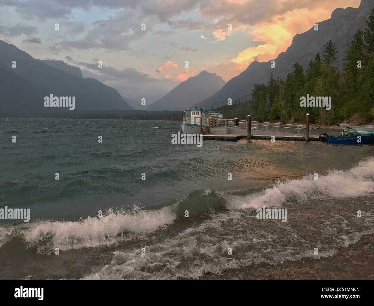 Tramonto sul lago di McDonald, il Parco Nazionale di Glacier. La storica DeSmet barca è appoggiata al dock. - Immagine stock catturata con smartphone