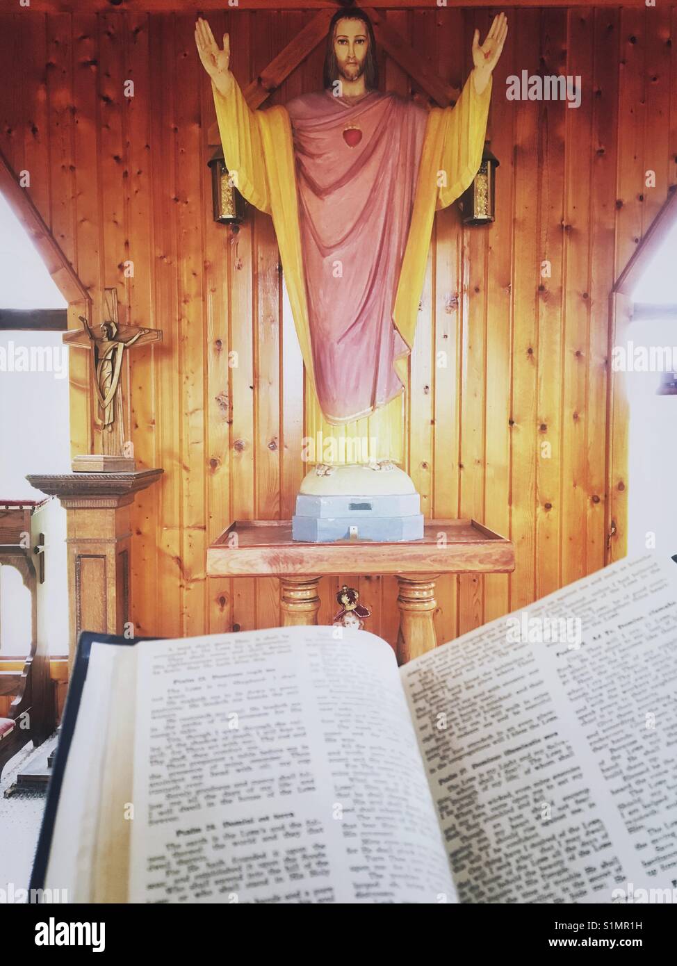 In legno statua di Gesù in una chiesa e aprire la Bibbia Foto Stock