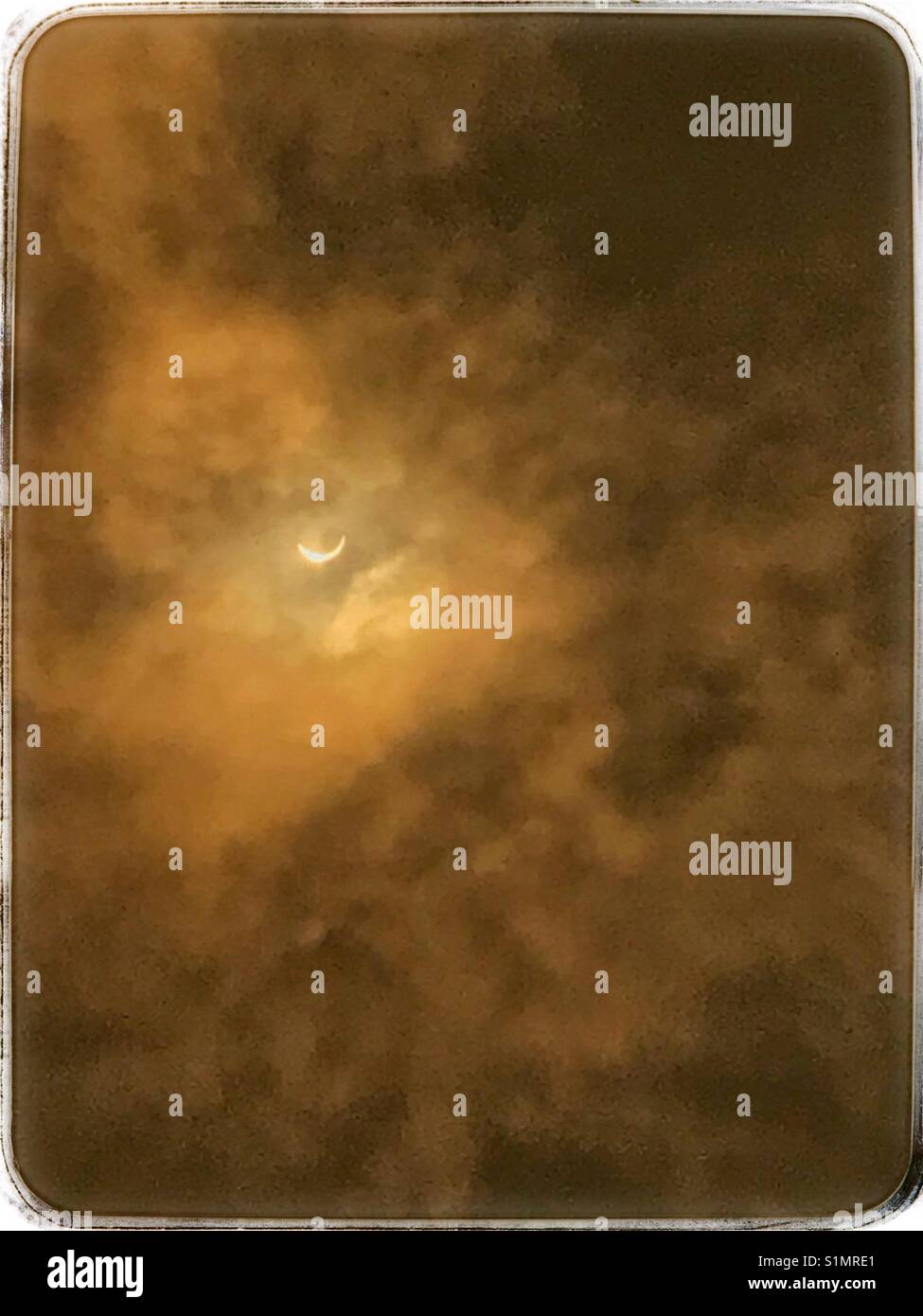 Eclissi solare visibile attraverso le nuvole nebuloso in colore seppia Jacksonville in Florida, 21 agosto 2017 - Immagine stock catturata con smartphone