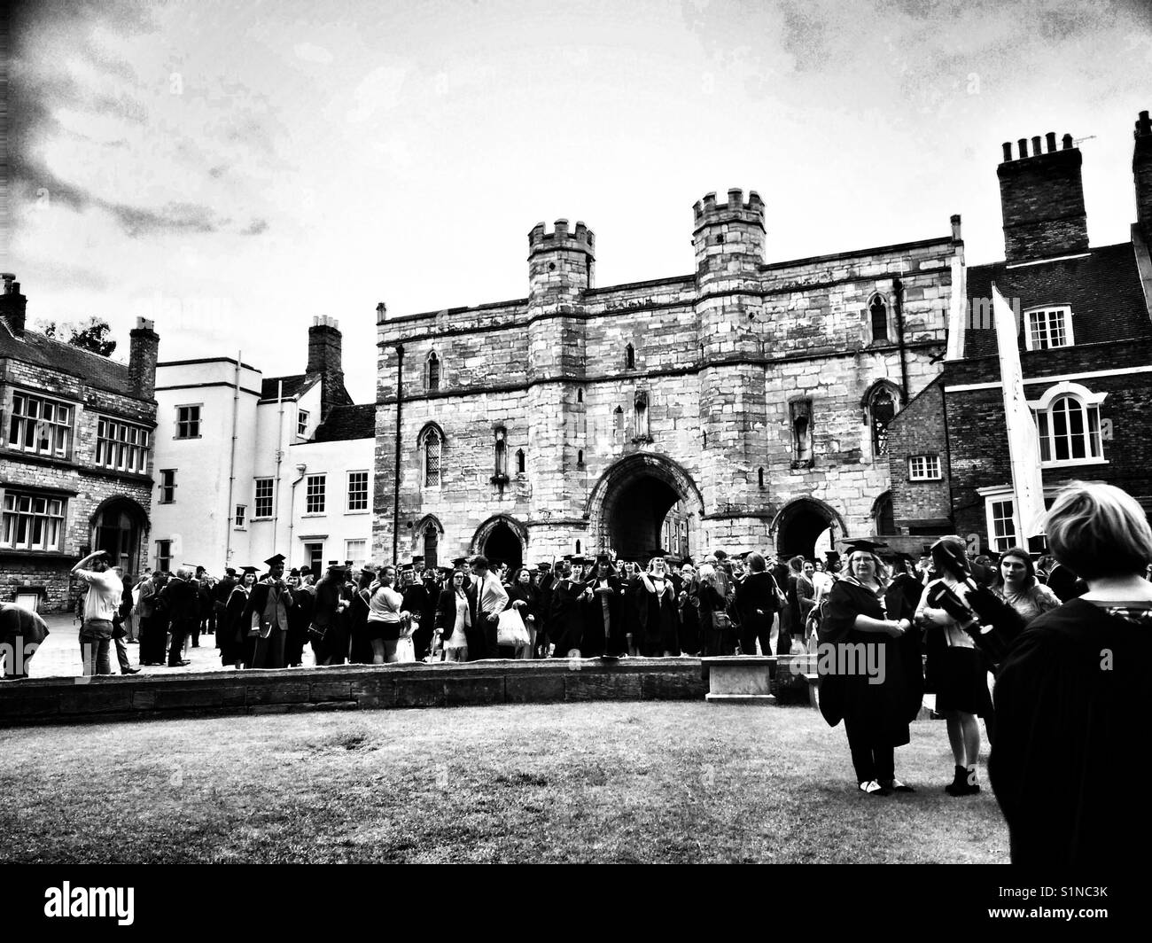 I laureati lasciando Cattedrale di Lincoln in seguito ad una cerimonia di laurea in bianco e nero. Foto Stock