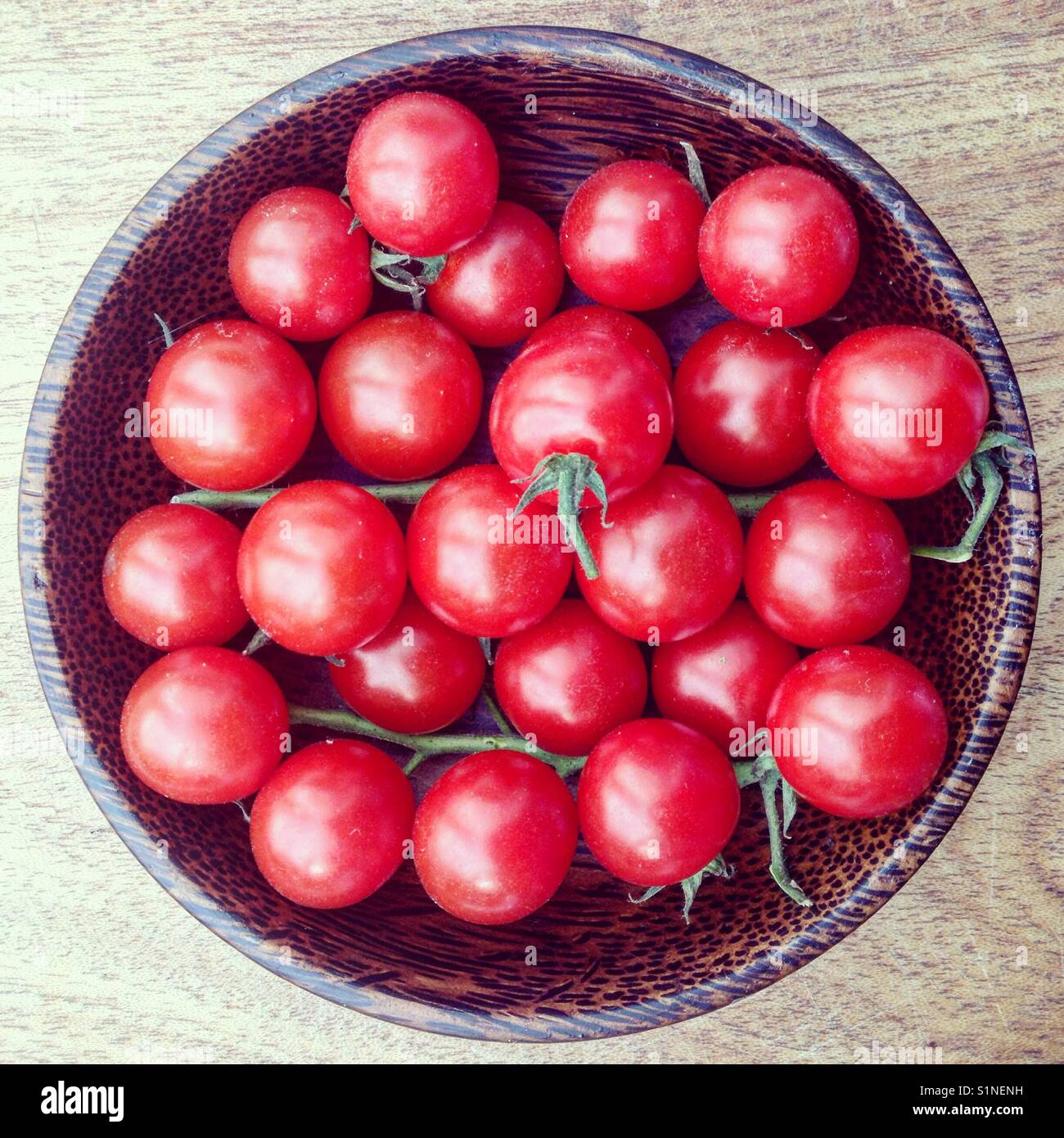 Ciliegia di colore rosso dei pomodori in una ciotola di legno - Immagine stock catturata con smartphone