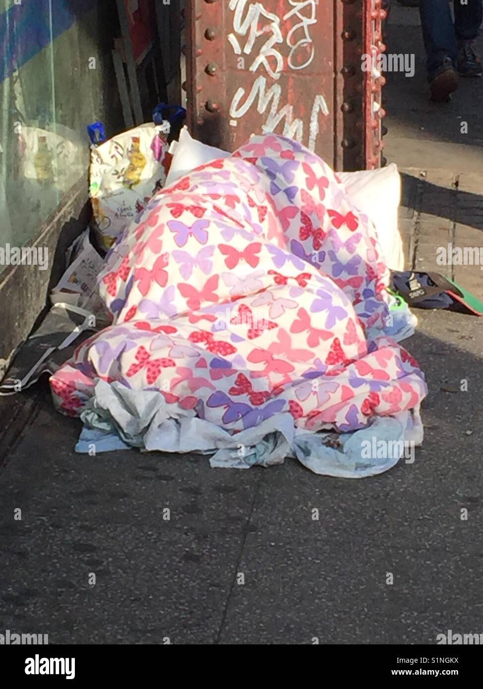 Una persona senza dimora sotto le coperte e piumini alla Stazione Waterloo di Londra in una fredda mattina Foto Stock