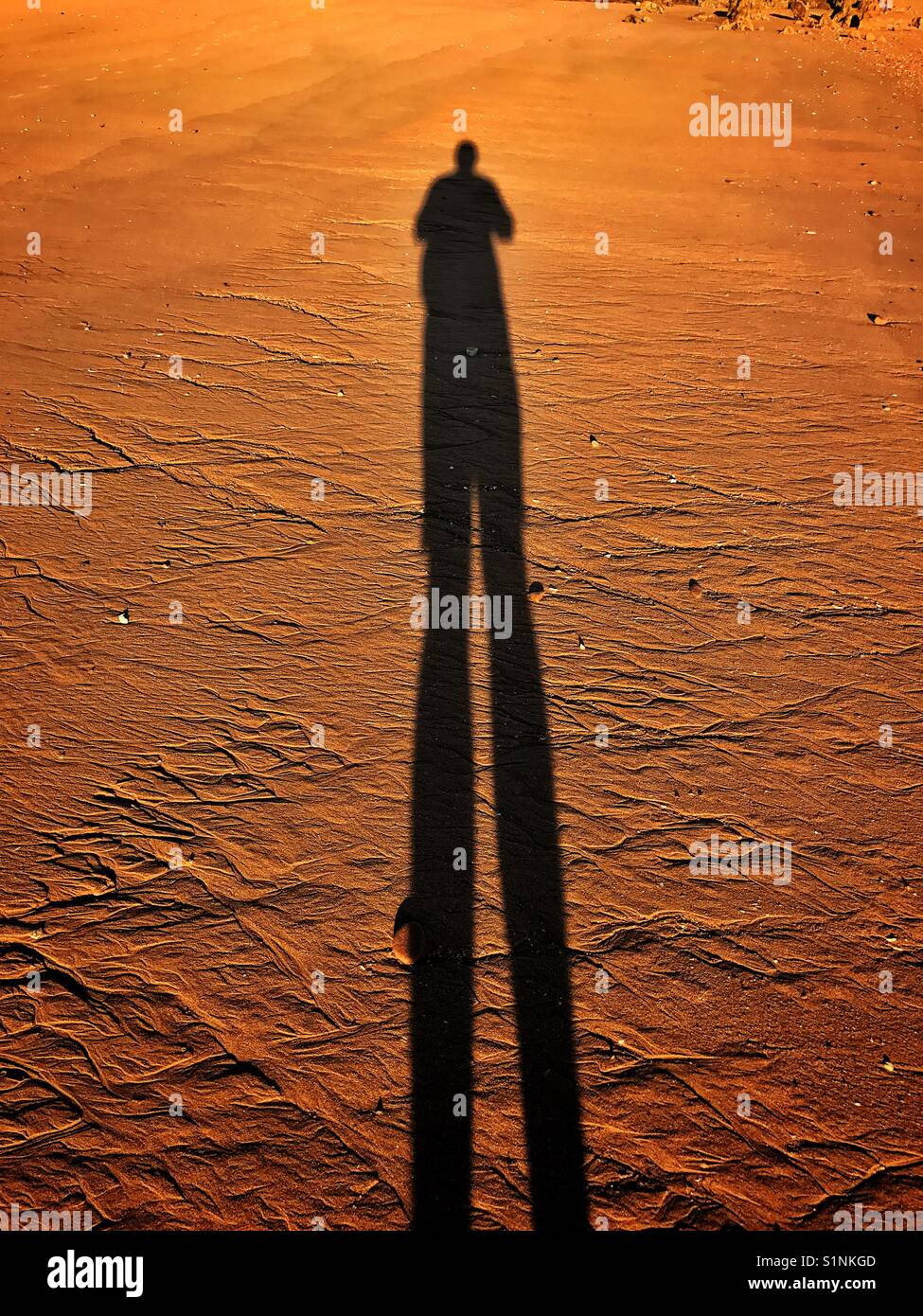 Lunga ombra umana in rosso sporco - Immagine stock catturata con smartphone