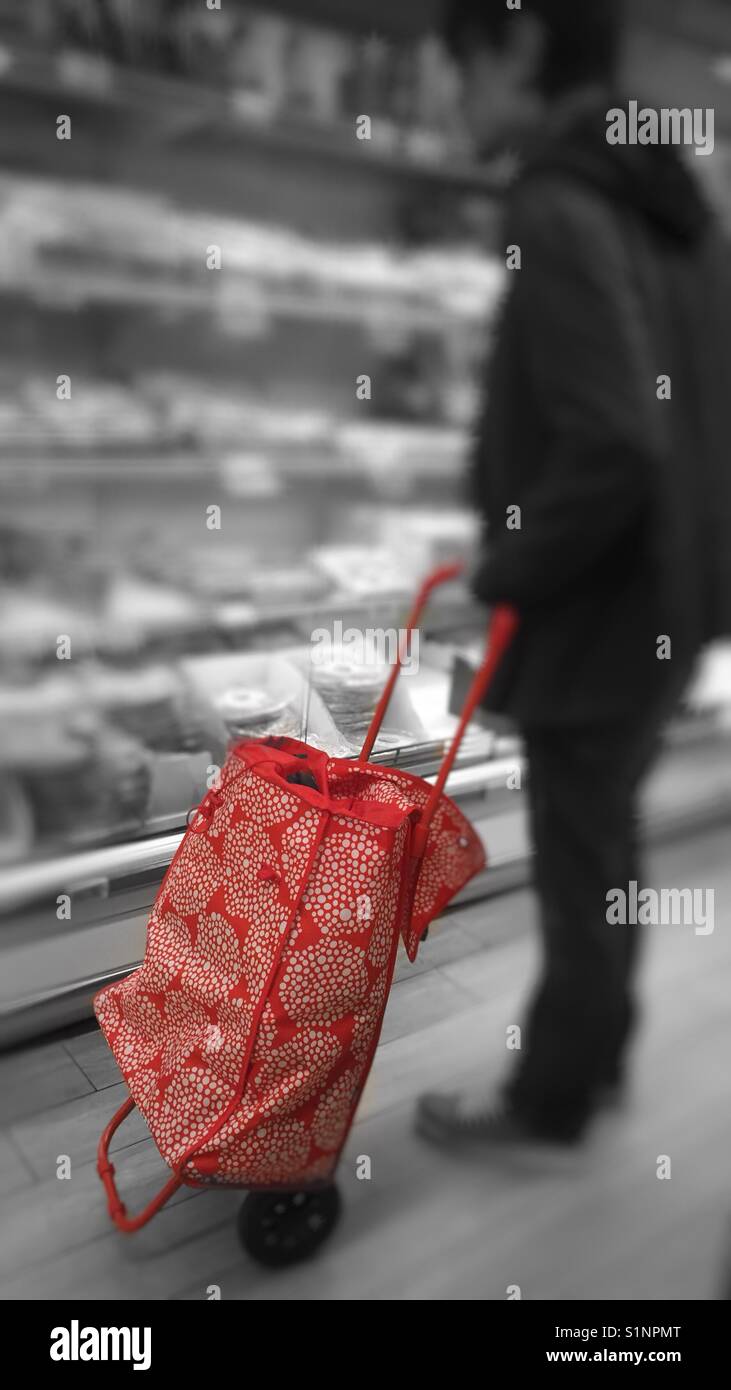 Uomo in piedi con un carrello della spesa in un supermercato guardando un frigo - Immagine stock catturata con smartphone