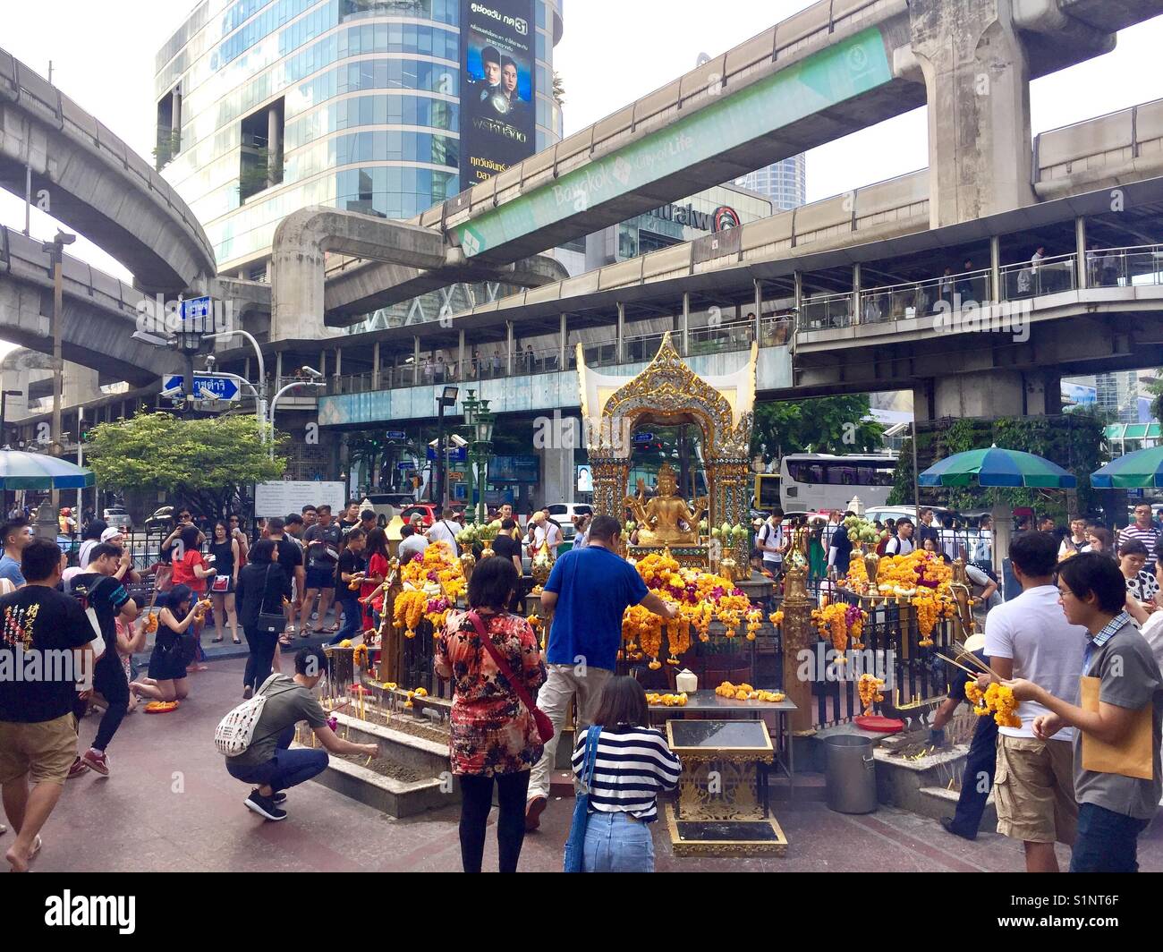 Thailandesi e turisti venuti e pagare i loro rispetti a quattro famosi Buddha di fronte al Santuario di Erawan alla giunzione Ratchaprasong in Bangkok Foto Stock