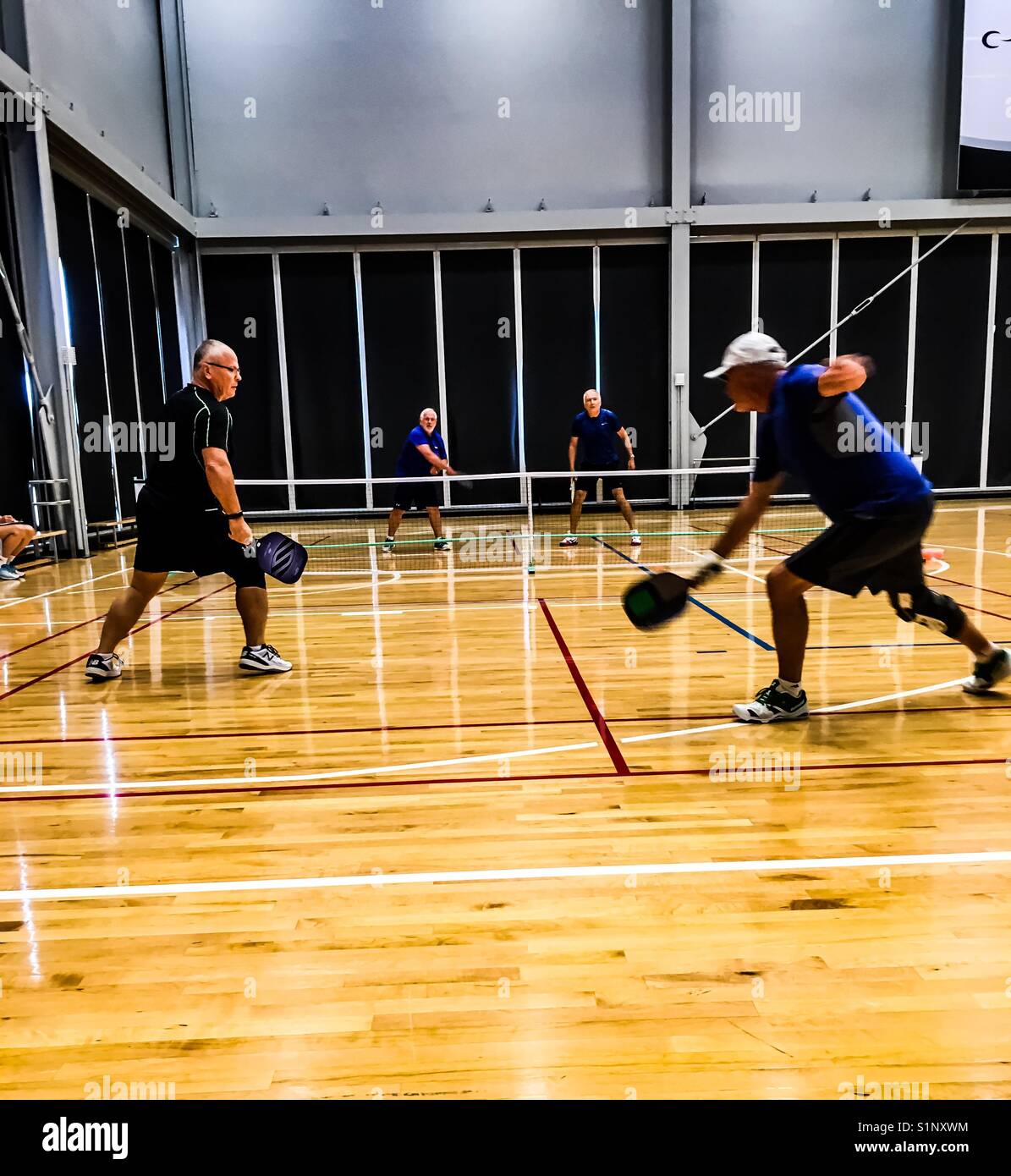 Raddoppia a Pickleball, una partita in corso al coperto, Ontario, Canada. Concetti: Competizione amichevole, lavoro di squadra, collaborazione, sport, atletica, pensionati. Palla di sottaceti. Uomini in gioco. Fratelli Foto Stock