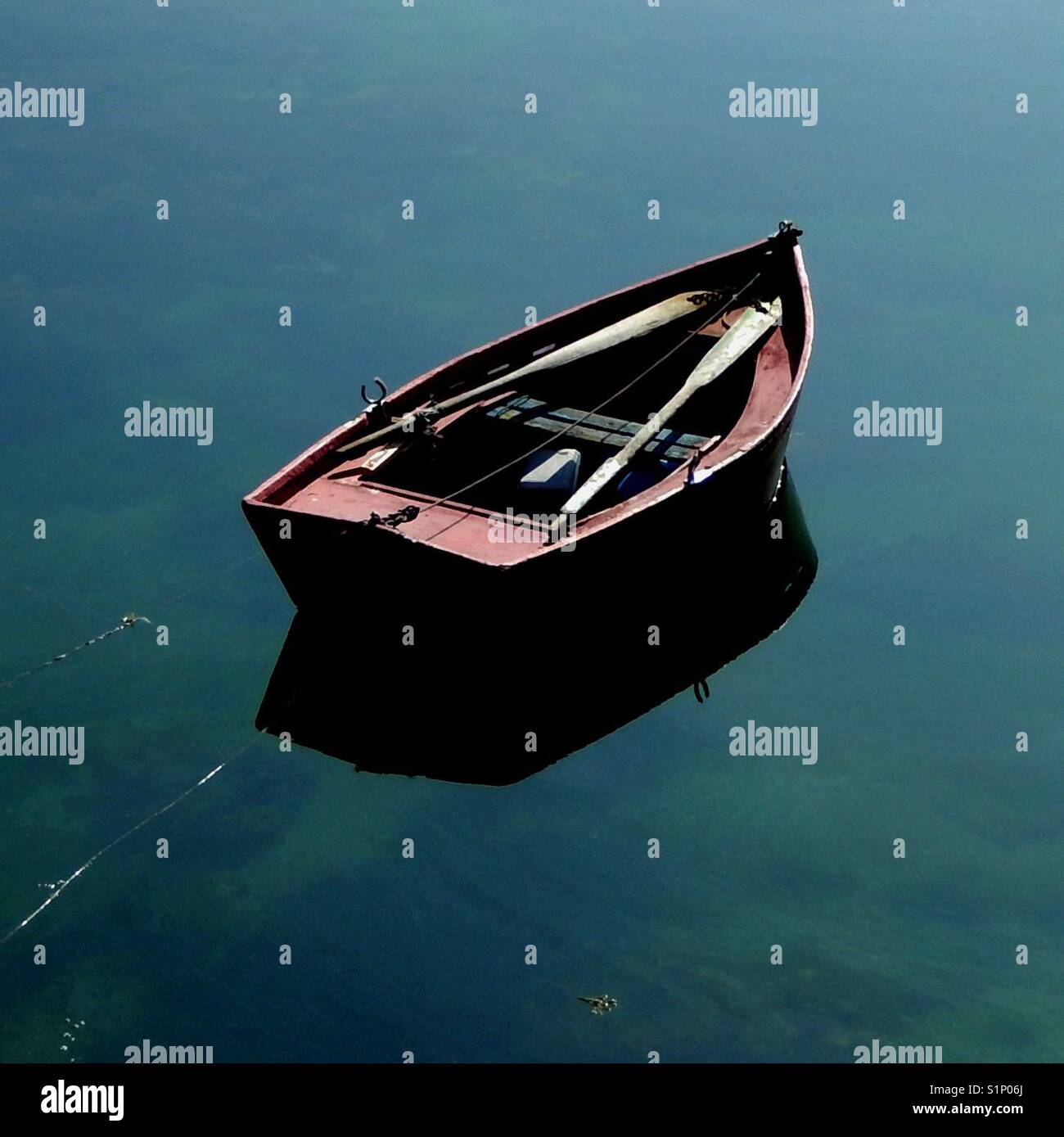 Barca a remi sulla superficie speculare di un lago Foto Stock