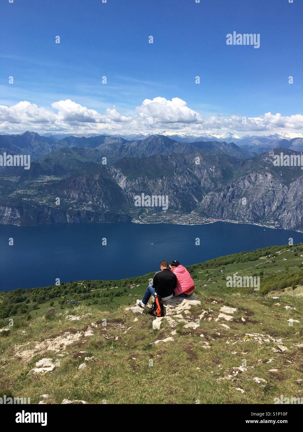 Una coppia in vacanza seduto su una roccia sul Monte Baldo che si affaccia sul Lago di Garda, Italia Foto Stock