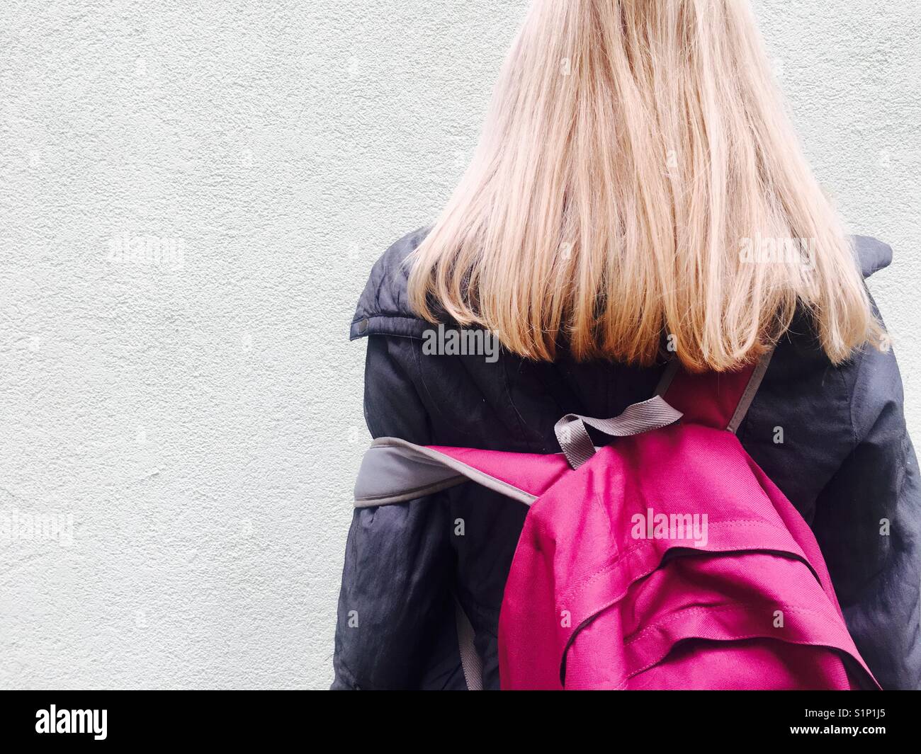 Una donna con un lungo e capelli biondi con magenta zaino rosa Foto Stock