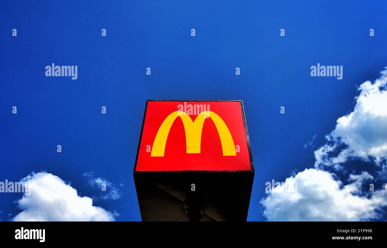 Il famoso McDonalds giallo M segno può essere trovato al di fuori di un ristorante fast food su una giornata d'estate. Il cielo è blu, le nuvole stanno cominciando a formare. Un sacco di spazio per la copia. Credito foto - © COLIN HOSKINS Foto Stock