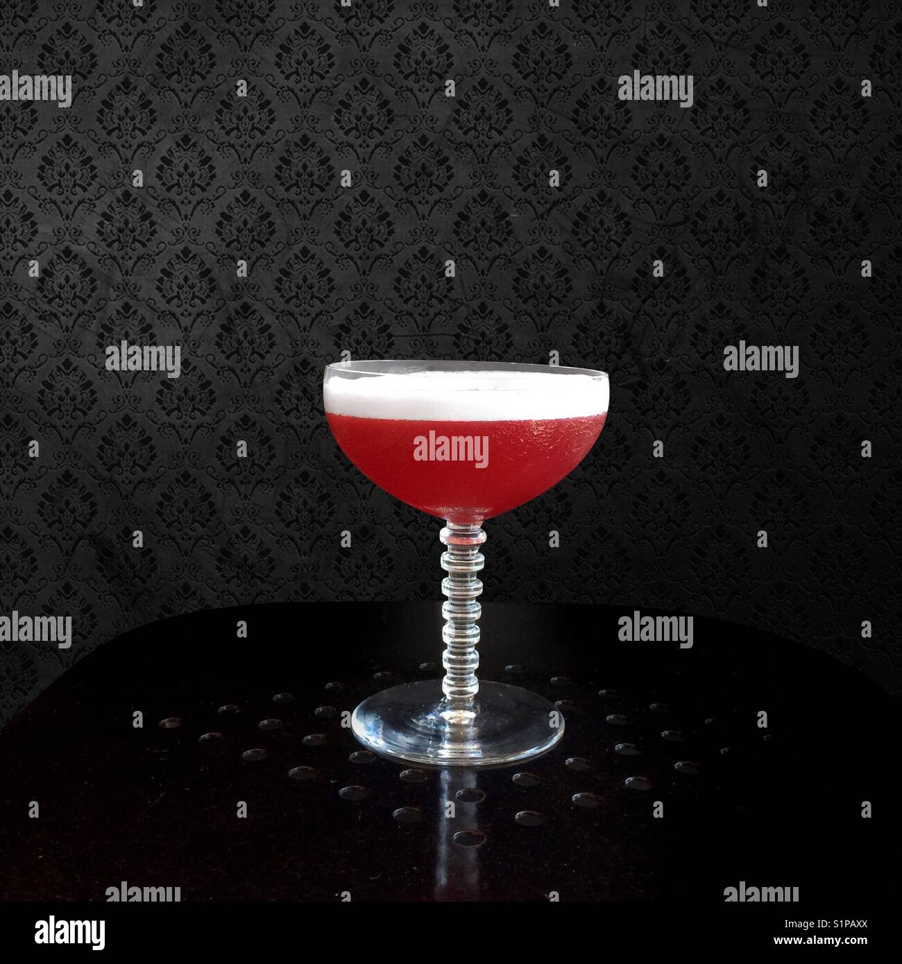 Solo cocktail in un elegante cocktail vetro contro una superficie strutturata su sfondo nero - Immagine stock catturata con smartphone