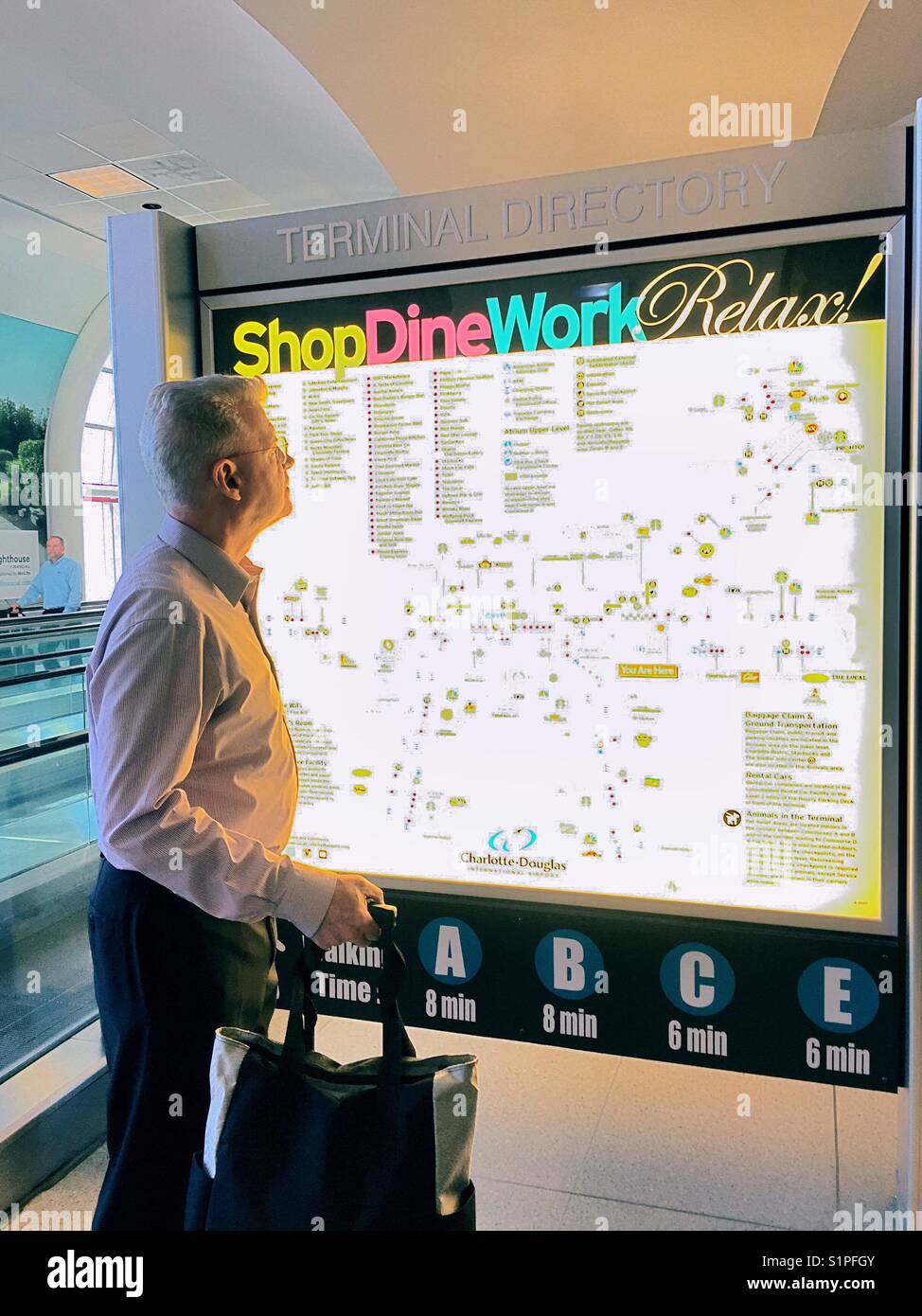 Senior uomo che viaggia e guardando alla mappa aeroporto segno, aeroporto Charlotte, North Carolina, STATI UNITI D'AMERICA Foto Stock