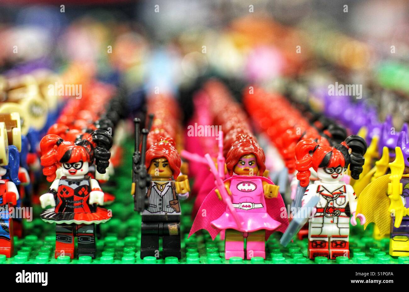 Righe di personaggi Lego come Harley Quinn di Batman serie allineate in un negozio per mini figure Foto Stock