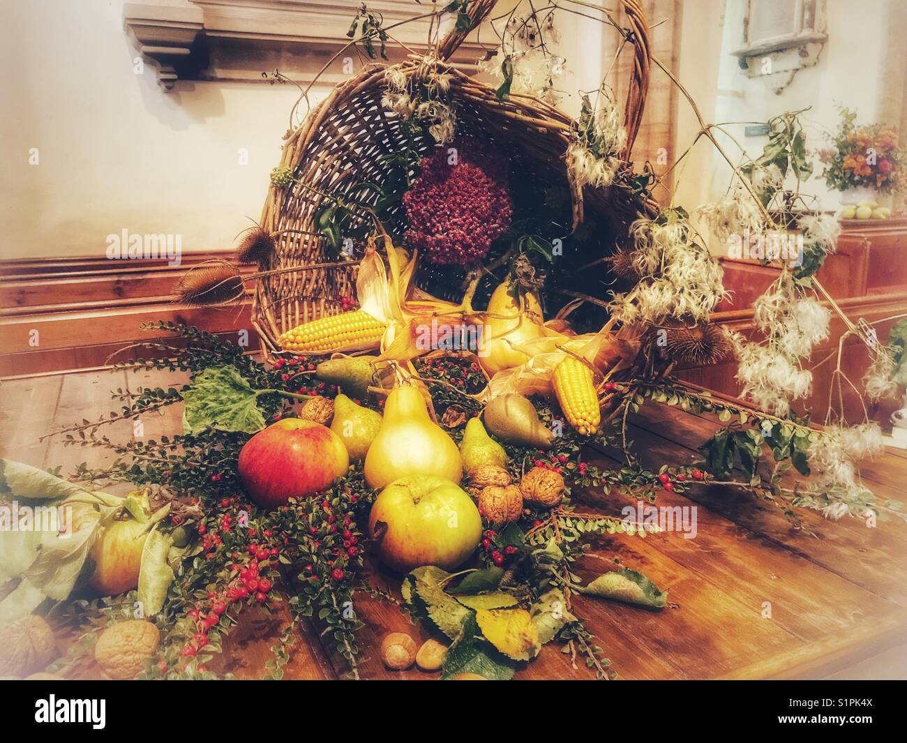 Harvest Festival in un villaggio inglese chiesa. cornucopia un simbolo di abbondanza traboccante di frutta, cereali e fiori. Foto Stock