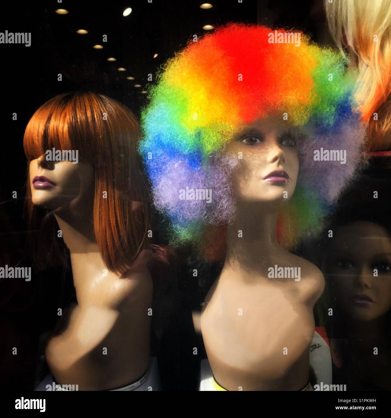Due teste di manichino in una finestra, una con un grande arcobaleno di colore afro Foto Stock