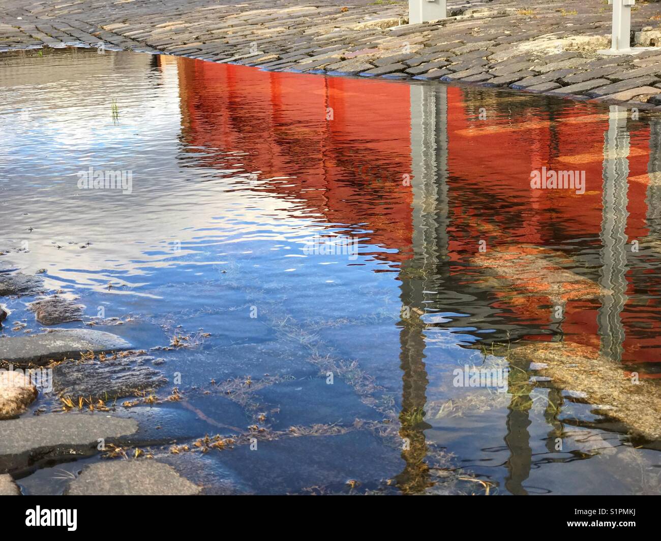 Edificio in mattoni rossi e cielo blu riflesso nell'acqua delle pozzanghere - Immagine stock catturata con smartphone