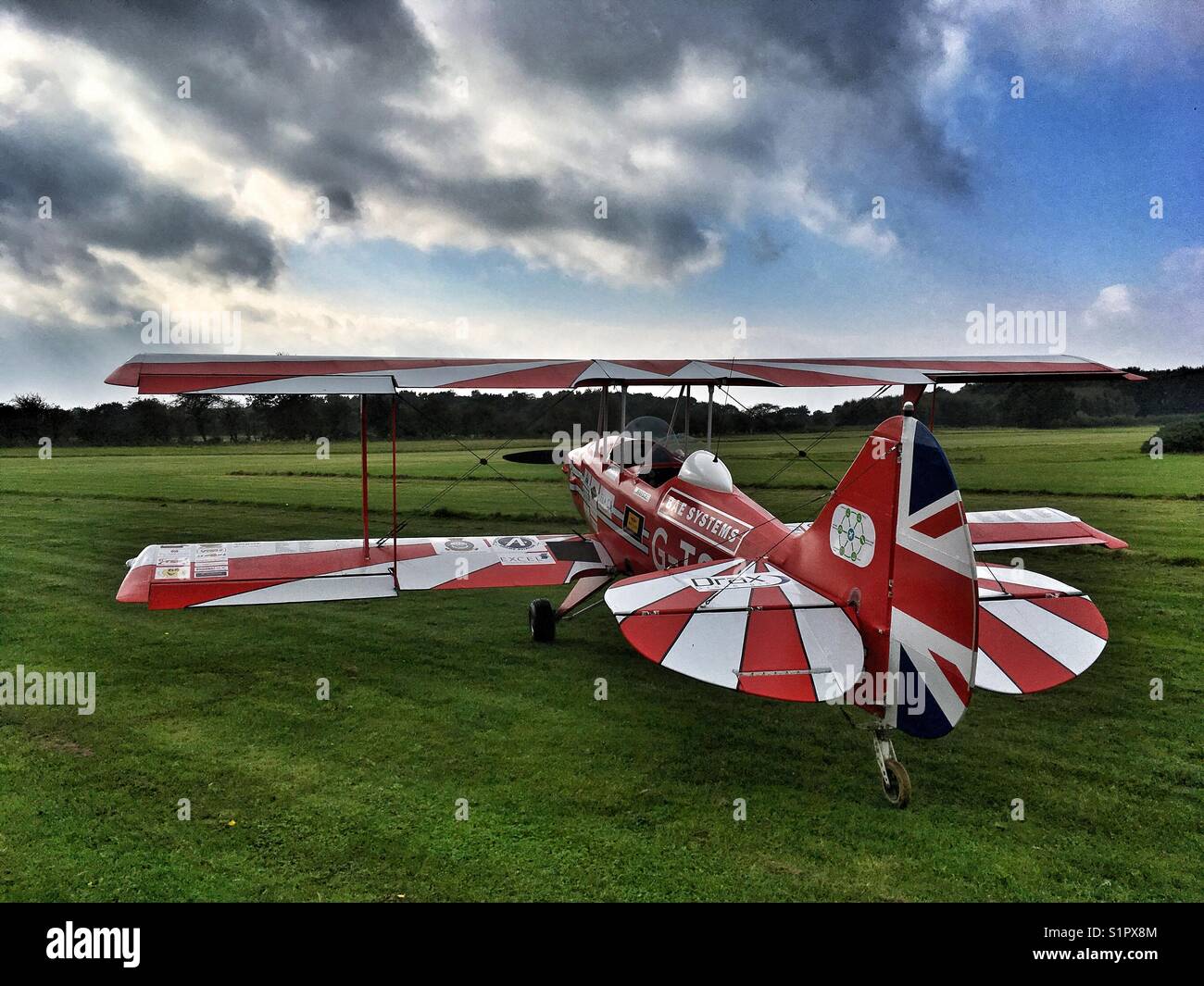 Il bianco e il rosso un biplano su un campo di aviazione di erba Foto Stock