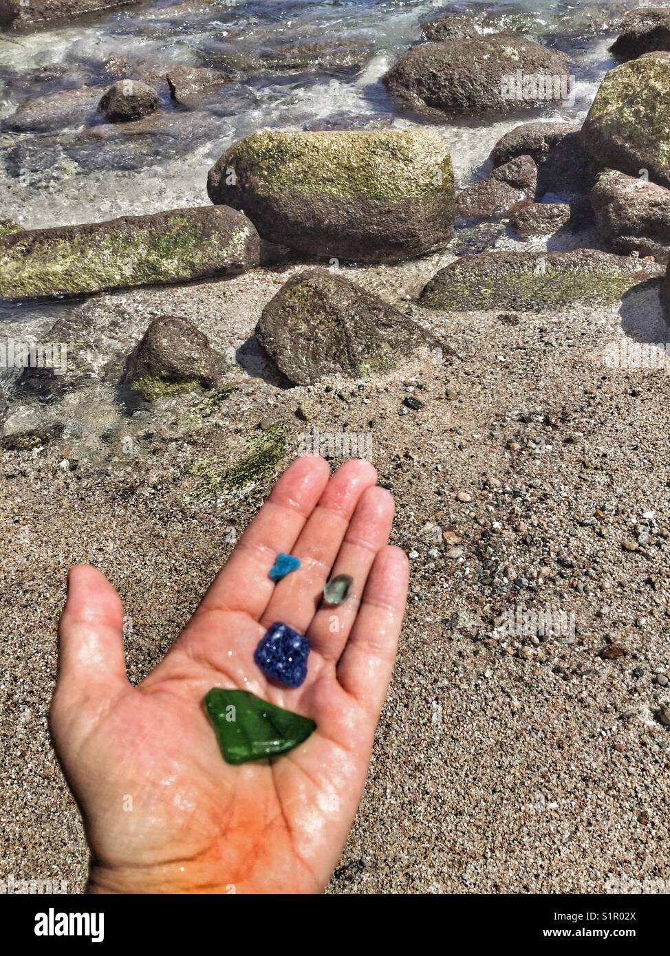 Vetro del mare formando una faccia felice nel palmo di una mano. Foto Stock