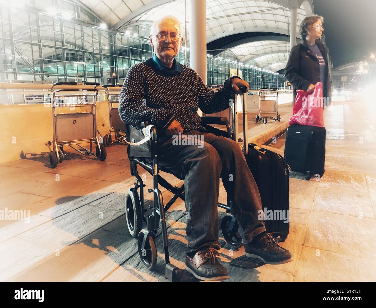 Senior di uomo e di una donna in attesa per il bus navetta per l'aeroporto di notte. El Altet, Alicante, Spagna. Foto Stock