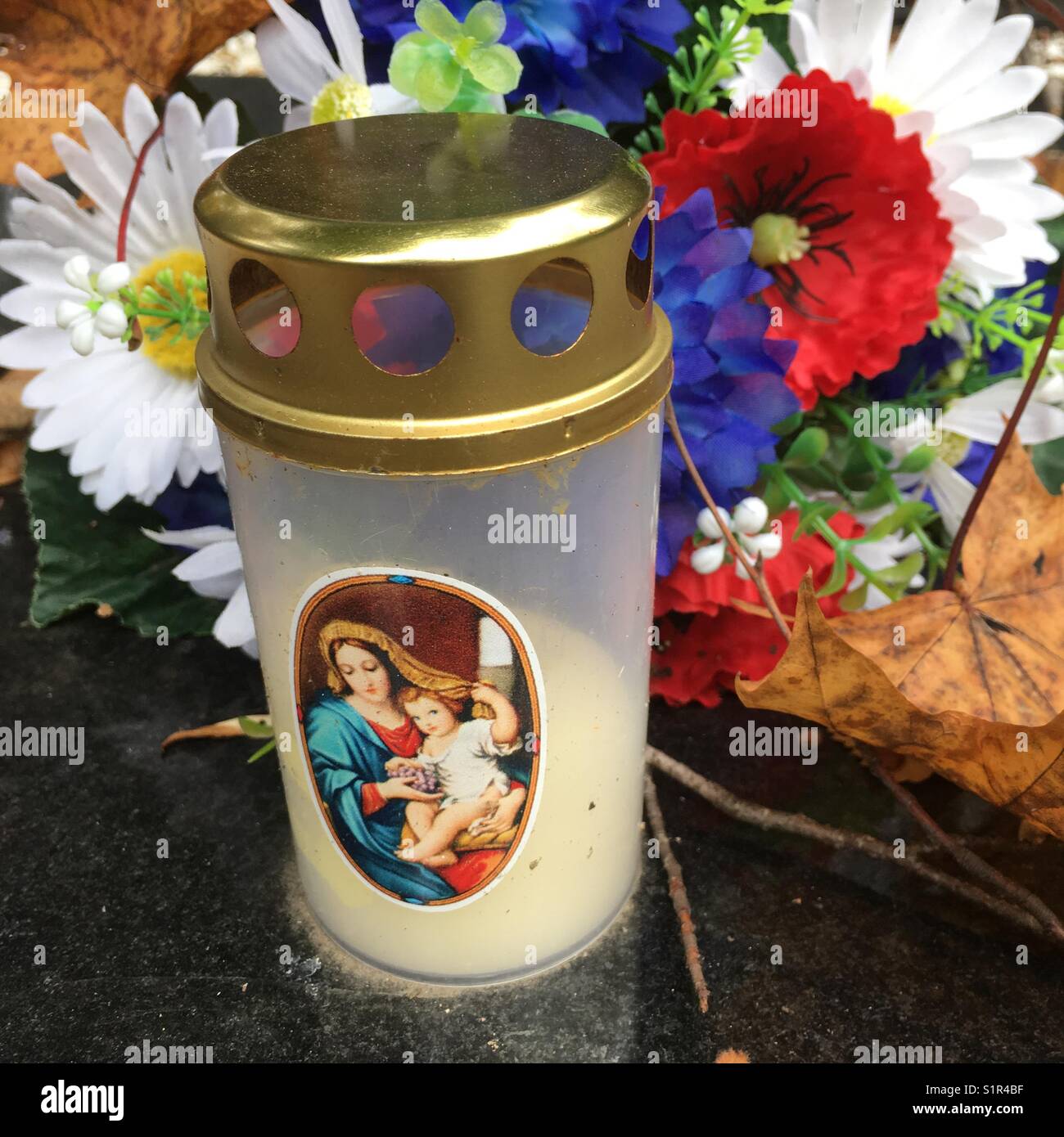 Candela sulla tomba con immagine della Vergine Maria e bacground fiori in plastica, Repubblica Ceca - Immagine stock catturata con smartphone