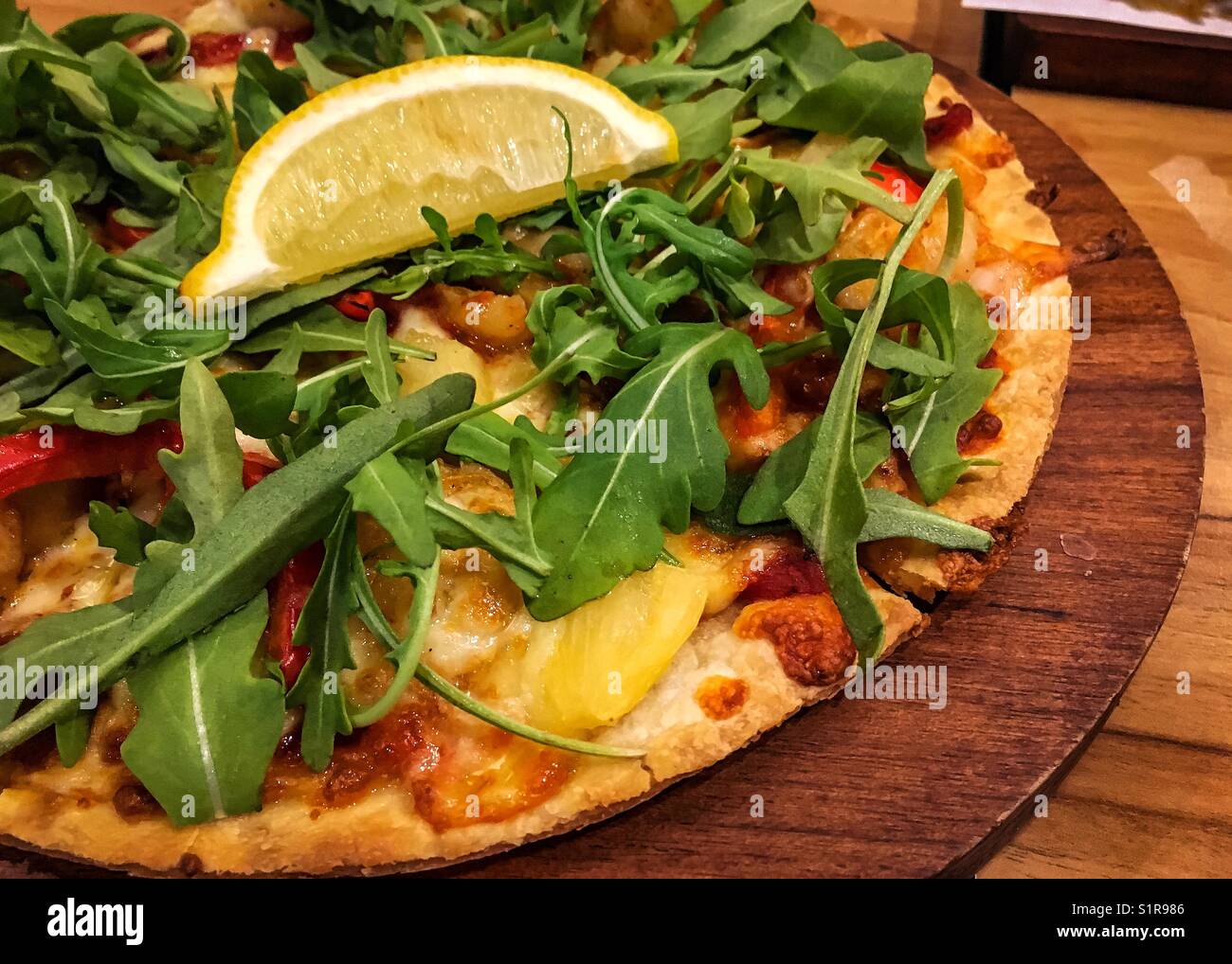 Pizza con salsa di pomodoro, verdure fresche e fette di limone nella vaschetta di legno Foto Stock