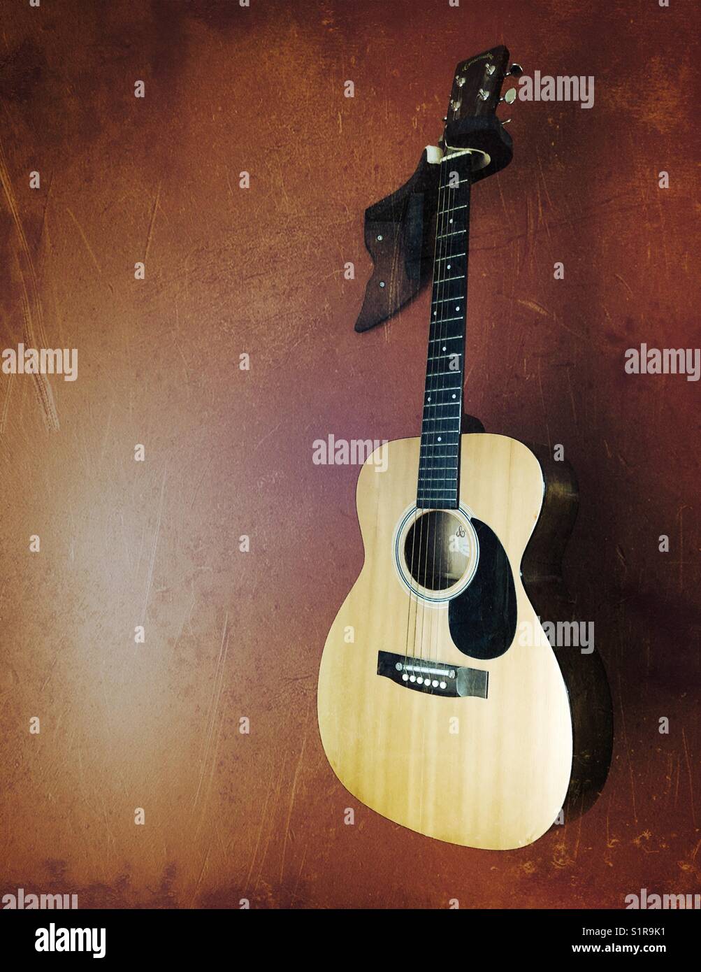 Ritratto di una chitarra acustica appesa a una parete - Immagine stock catturata con smartphone