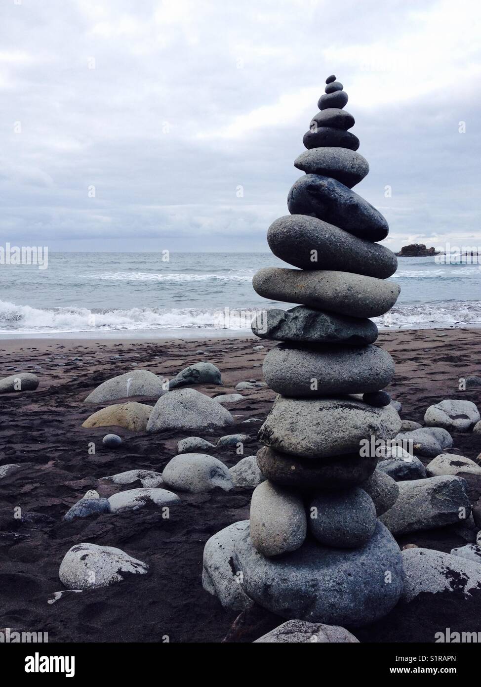 Bilanciamento del rock - tall pilastro delle rocce su di una spiaggia di sabbia nera, nord tenerife Foto Stock