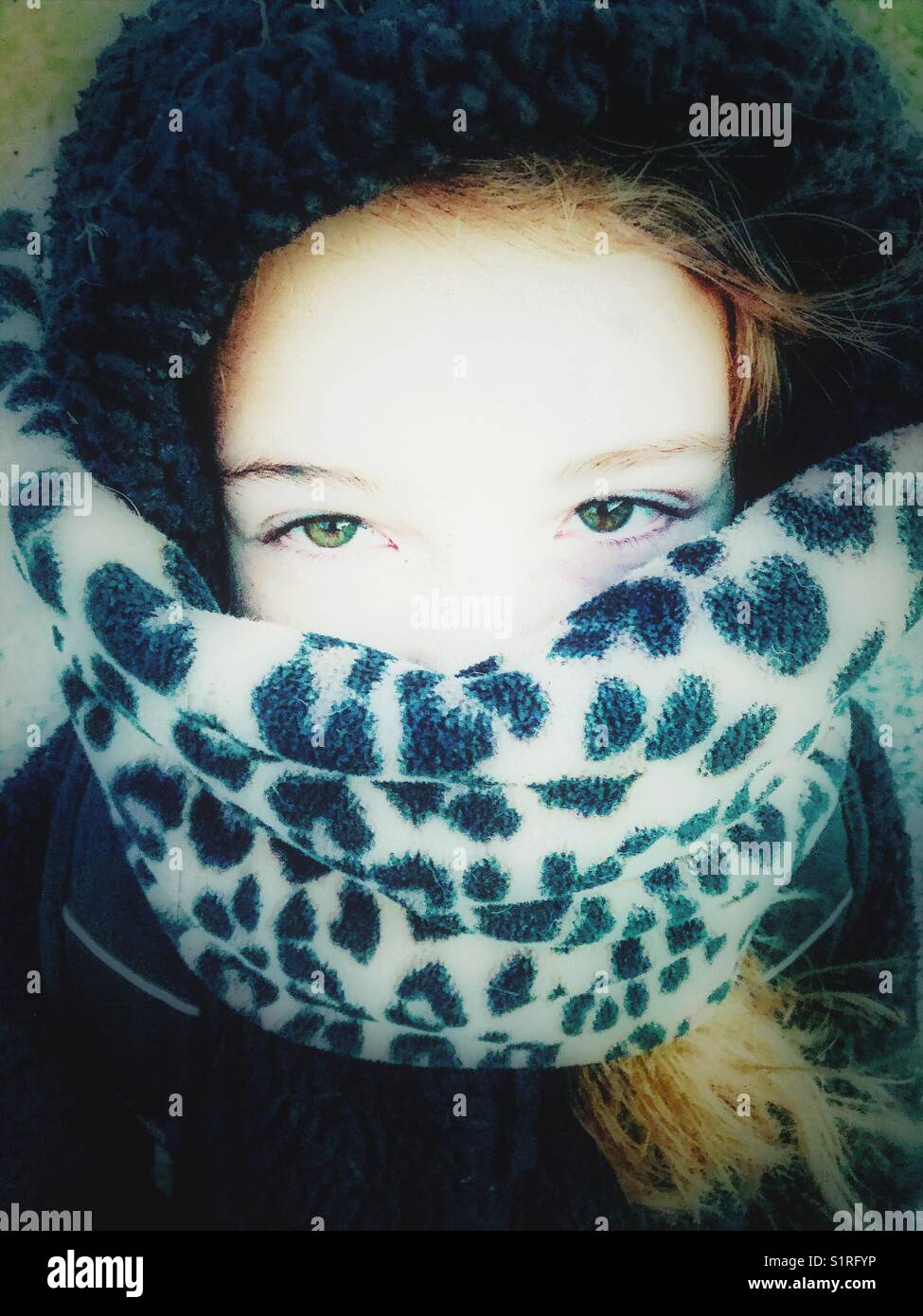 Ragazza con ampi occhi verdi che indossano un cappuccio e una sciarpa in pile con stampa ghepardo per tenersi al caldo Foto Stock